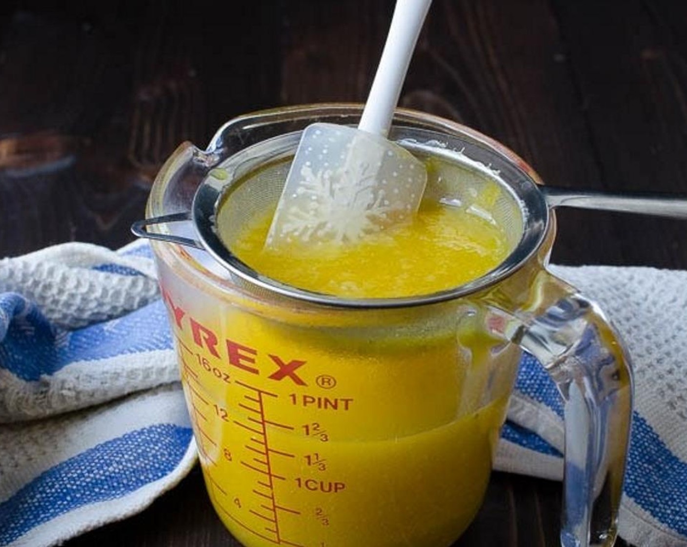 step 10 Place a fine mesh strainer over a small bowl and carefully pour the lemon curd through the strainer. Use the back of a spoon or small spatula to press the curd through the strainer -- this will remove the lemon zest and any stray seeds that made it into the curd.