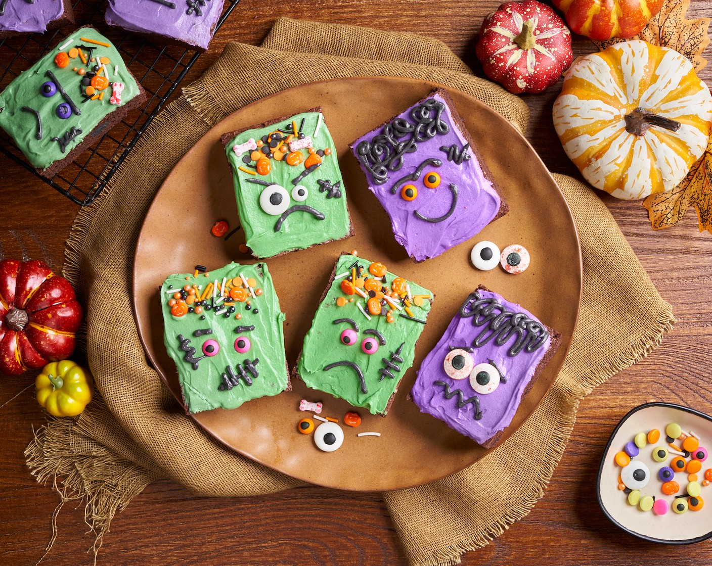 step 9 For the purple brownies, use black frosting to draw the hair, mouth, and stitches. And put on Candy Eyeballs (as needed).