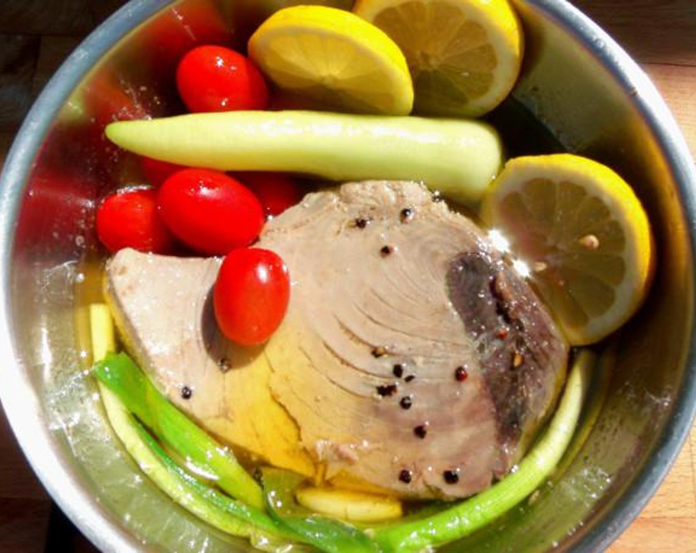 step 1 Simmer Slowly Scallion (1 bunch), Kosher Salt (to taste), Freshly Ground Black Pepper (to taste), Grape Tomatoes (5), Quintisho Chili Pepper (1), and Lemons (3 slices) on low heat basting with Extra-Virgin Olive Oil (1 cup) until Canned Tuna (1 can) is cooked to your preferred temperature