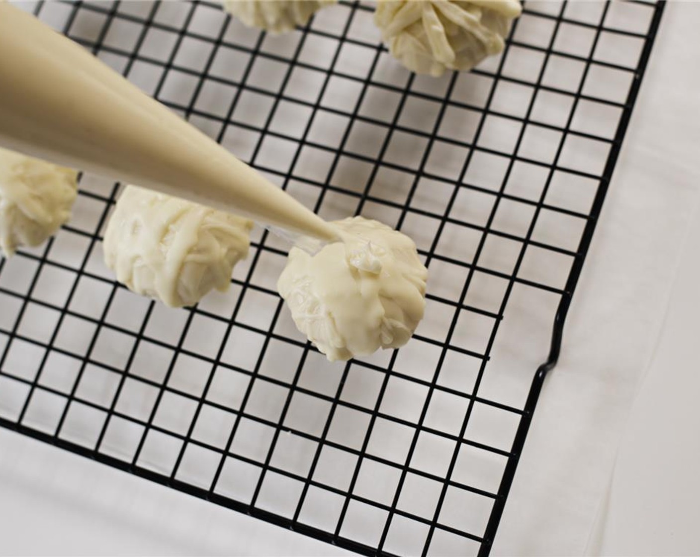 step 12 Add remaining melted chocolate to a piping bag. Remove cake truffles from the refrigerator and begin piping "bandages" across the tops of each.