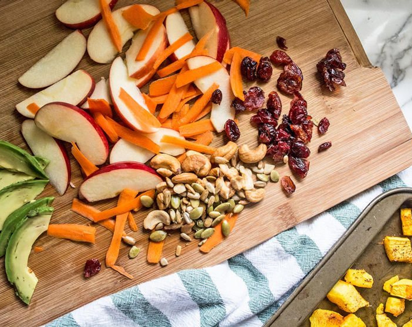 step 5 Once butternut squash has roasted and cooled, assemble salad by dividing Fresh Baby Spinach (4 cups) between two large bowls. Top with Apple (1), Carrot (1), Avocado (1/2), Unsalted Cashews (4 Tbsp) and Dried Cranberries (4 Tbsp).