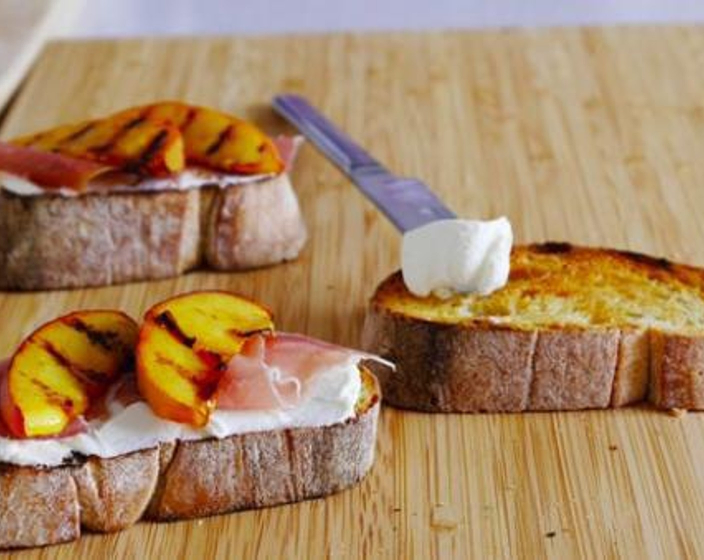 step 3 Once done, build the bruschetta adding an abundant layer of Philadelphia Original Soft Cheese (1 cup), then a slice of Prosciutto (4 slices), and 2 or 3 slices of peach.