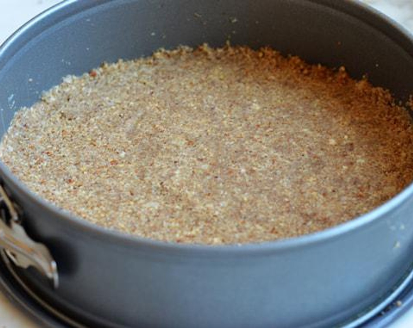 step 4 Transfer the crust mixture to a greased springform pan. Pat into an even layer, then set aside.