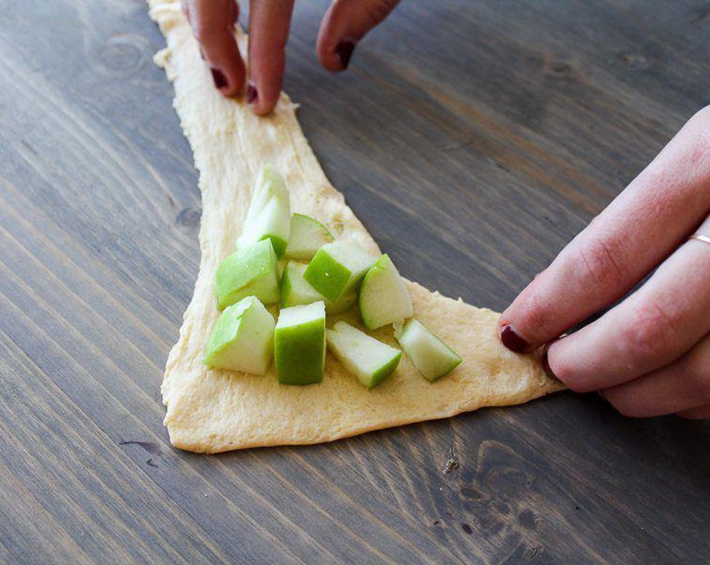 step 4 Carefully unroll the Crescent Roll Dough (2 pckg) and separate into triangles. Place a small handful of apple pieces, about 2 tablespoons per triangle, in the center of each crescent.