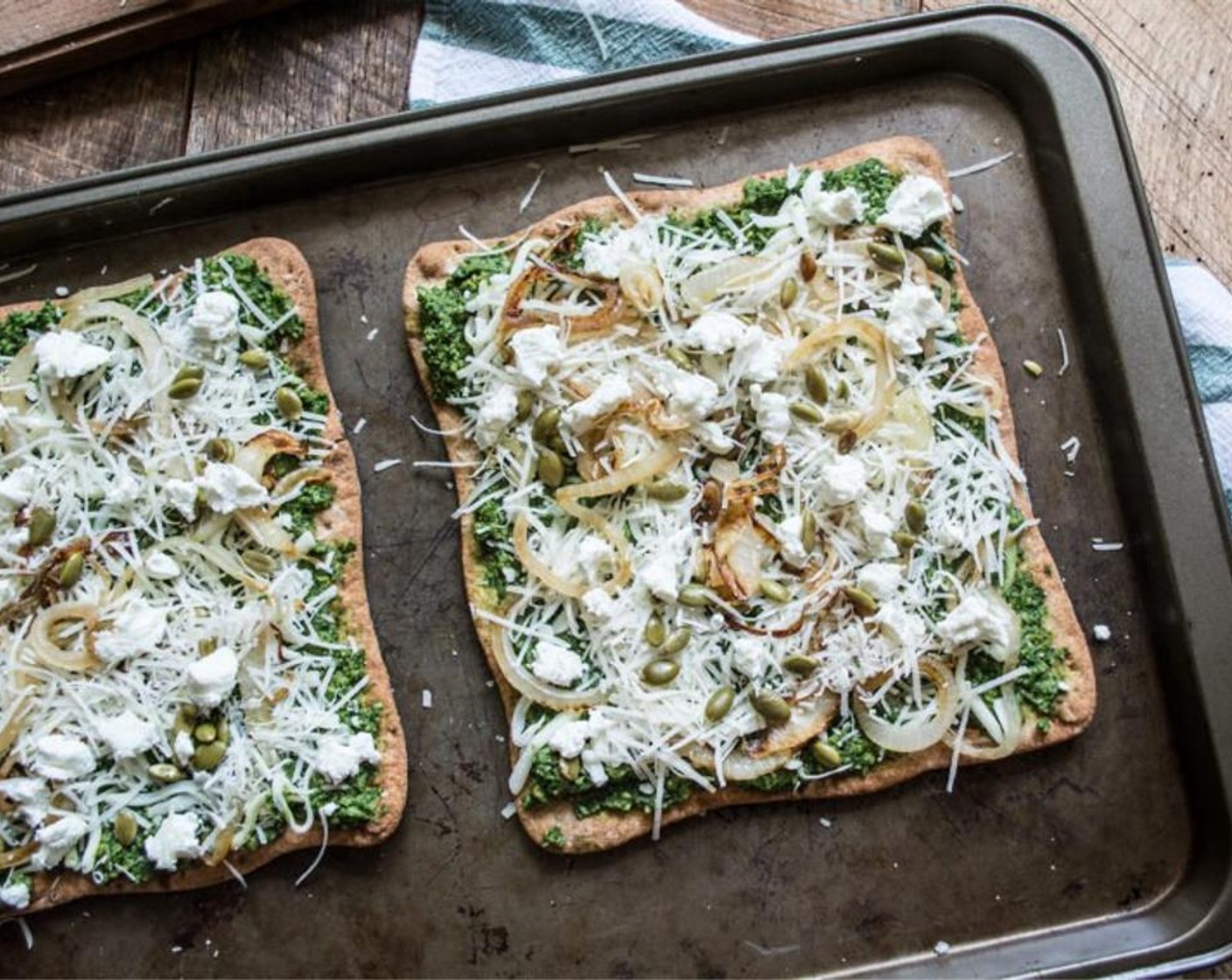 step 6 Remove flatbread from oven, add pesto, Mozzarella Cheese (1/2 cup), Parmesan Cheese (1/2 cup), onion, Goat Cheese (3 Tbsp), Roasted Pepitas (1 Tbsp). Bake for an additional 5 mins or until the cheeses have melted.