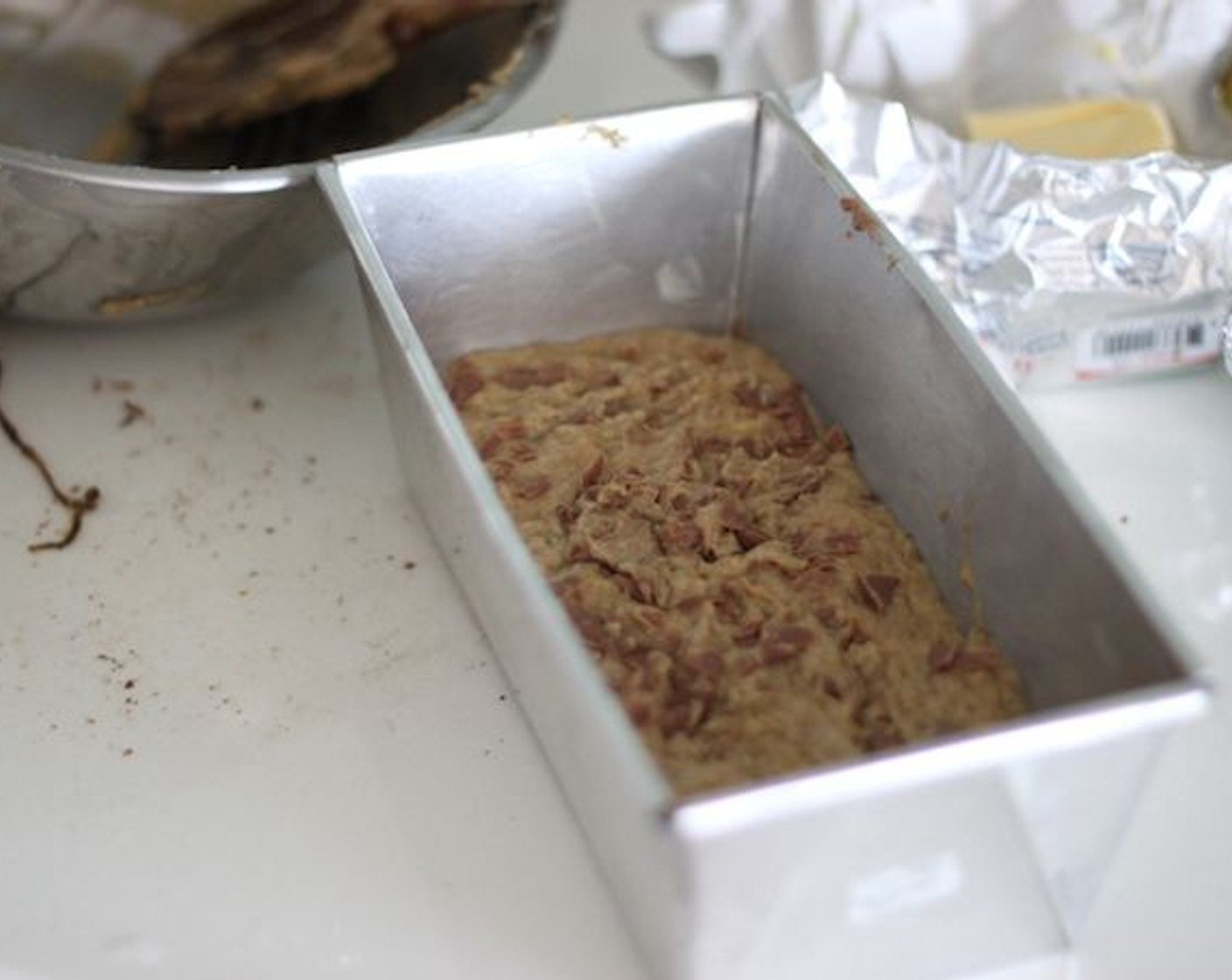 step 8 Butter your loaf pan and start pouring the mixture in. Your loaf pan should be 4×8-inch (10×20 centimeters). I put the baking sheet on the bottom of the loaf pan so it’s easier to take the bread out.