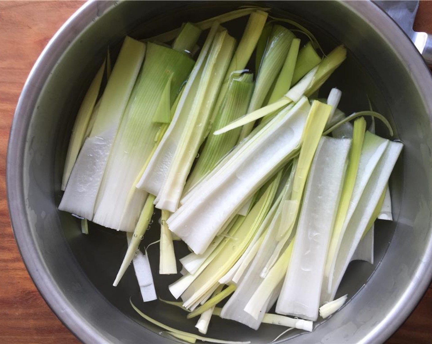 step 2 Place the leek into a large bowl of cold water. Agitate the pieces to make sure any dirt falls to the bottom of the bowl. Let sit for 5 minutes.