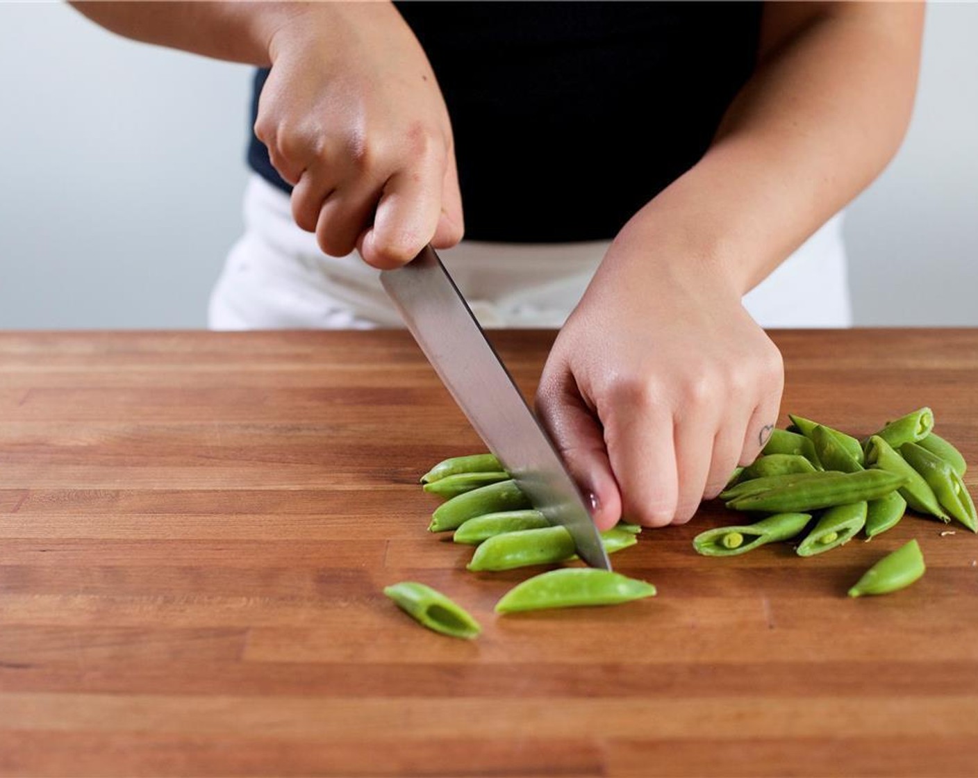 step 2 Meanwhile, cut the Sugar Snap Peas (1 cup) in half on a diagonal, and set aside. Slice the Shallot (1) in half lengthwise, then into quarter inch moons. Set aside.