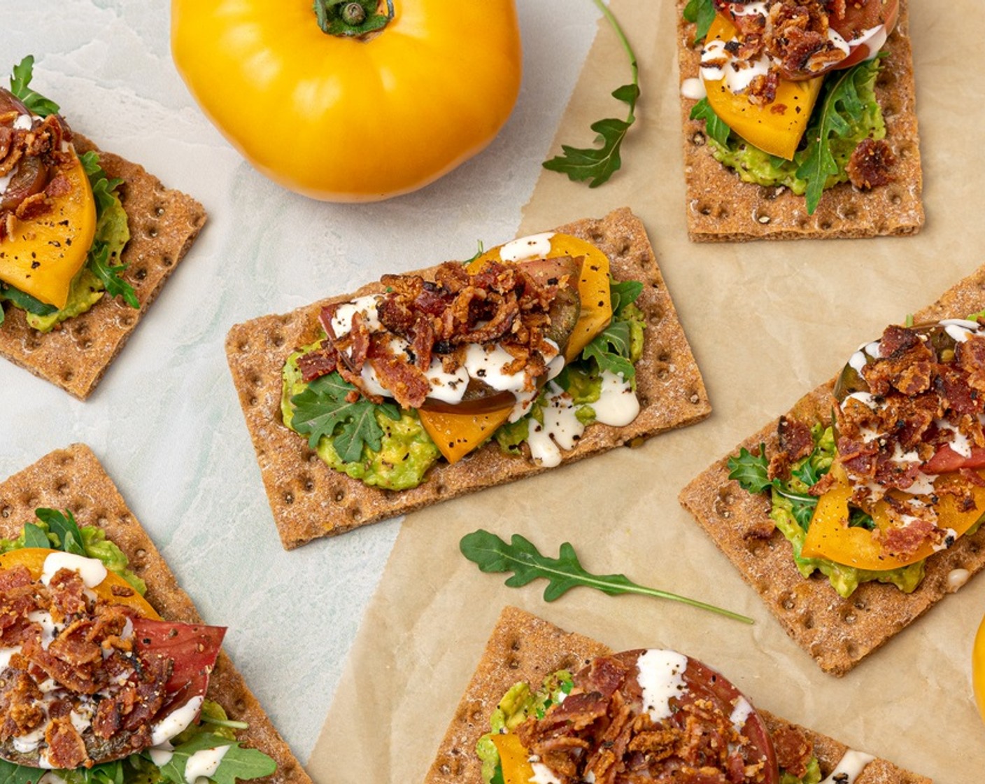 step 6 To serve, spread Avocado (1) on each Crispbread (8 slices). Top with Baby Arugula (1 cup) and Heirloom Tomatoes (2), then drizzle with aïoli and sprinkle with bacon and Freshly Ground Black Pepper (to taste). Serve immediately.