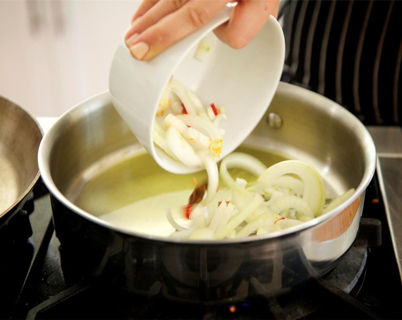 step 7 Heat a medium saute pan over medium high heat. Add Olive Oil (3 Tbsp). When the oil is hot and close to smoking point, add the onion, thai chili, Cinnamon Stick (1), and Star Anise (1). Saute for three minutes until onions are soft and translucent.