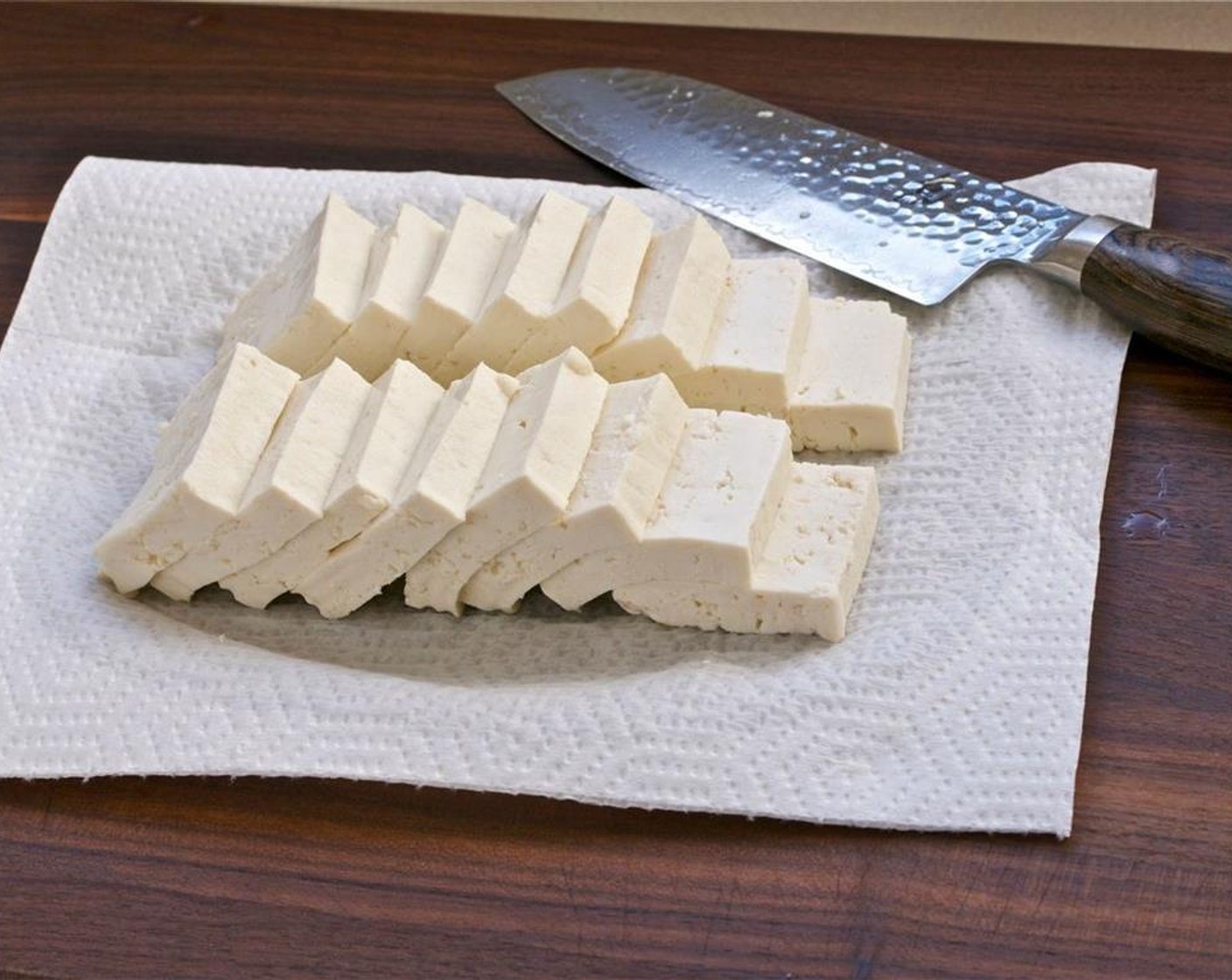 step 4 Place the Firm Tofu (1.1 lb) on top of two layers of paper towels over the cutting board. Cut the tofu in half and slice each half into equal slices.