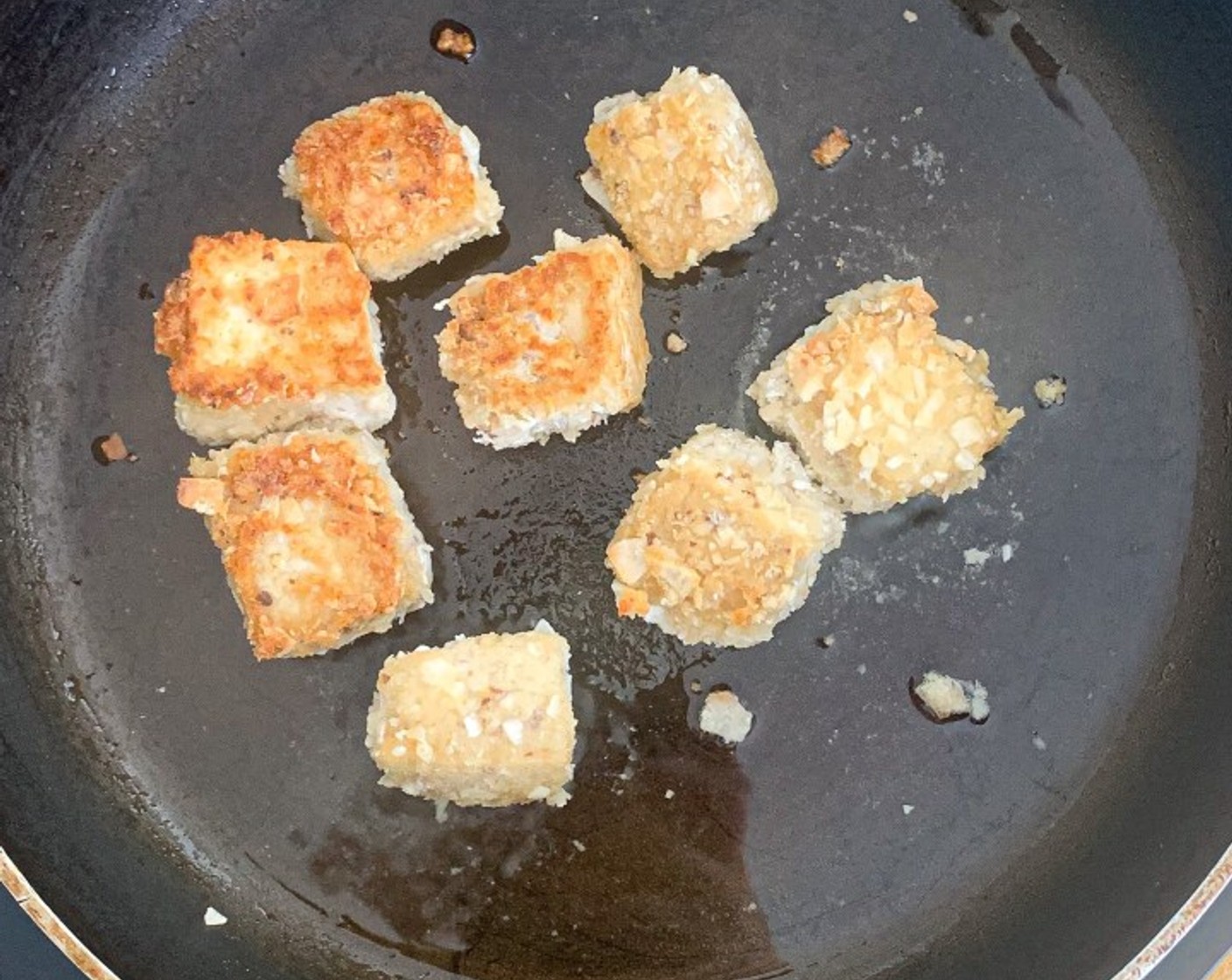 step 12 Once the oil is heated, place 1/5 of the crusted coconut into the skillet or pan and fry each side until it is golden brown. This will likely take 3 minutes on each side.