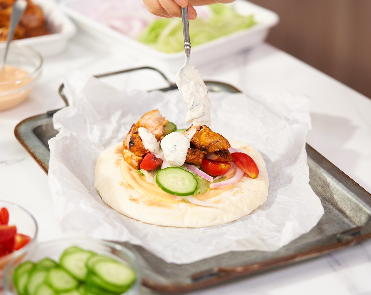 step 7 To assemble the wrap, top a warm Flatbread (4) with spicy mayonnaise, Lettuce (to taste), Red Onions (to taste), Tomatoes (to taste), Cucumbers (to taste), sliced chicken, and yogurt sauce.