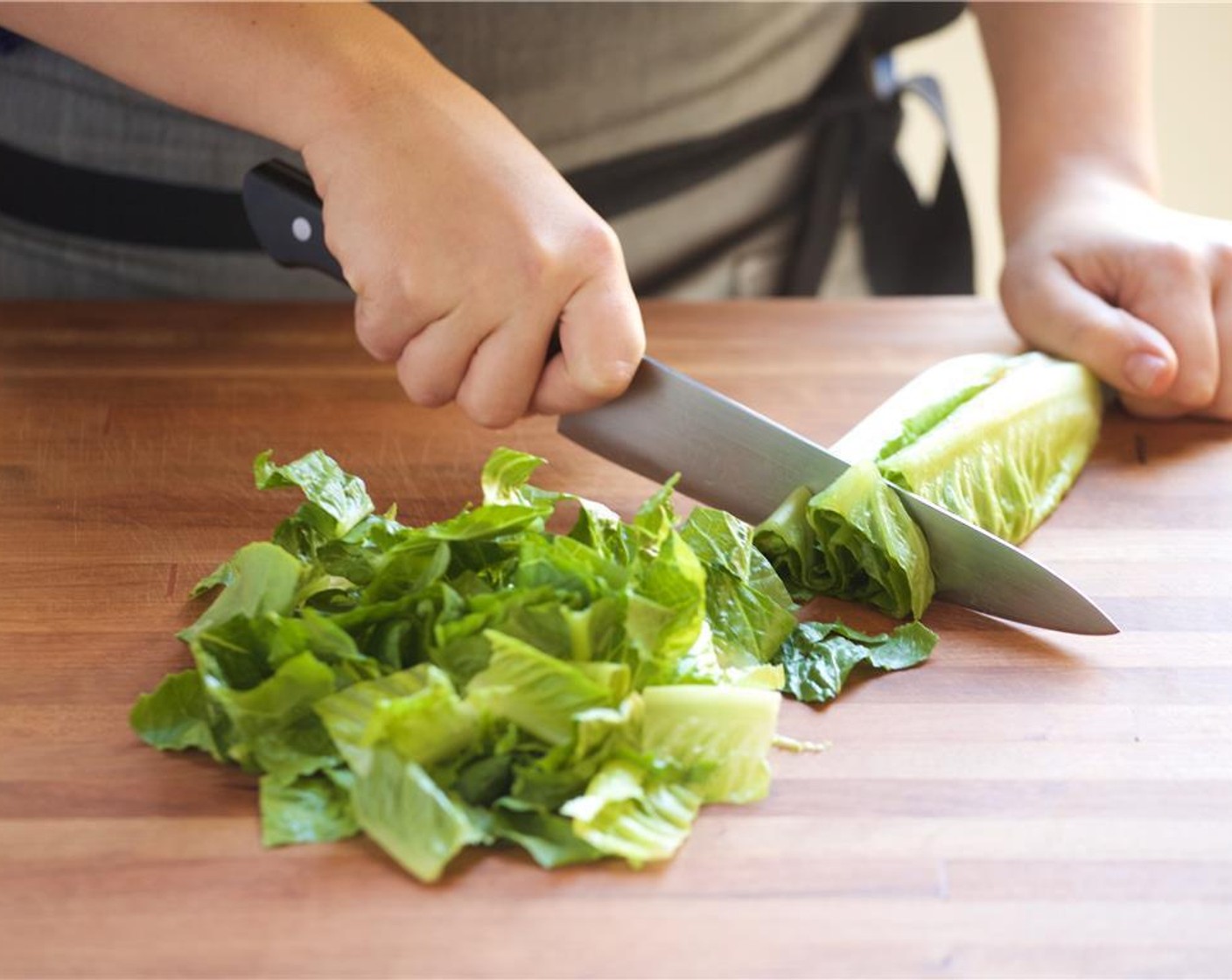 step 3 Slice the Romaine Lettuce (2 heads) in half lengthwise. With the cut side facing upwards, remove the core with your knife and discard core. Next, slice the romaine across into half inch thick slices. Add to a large bowl.