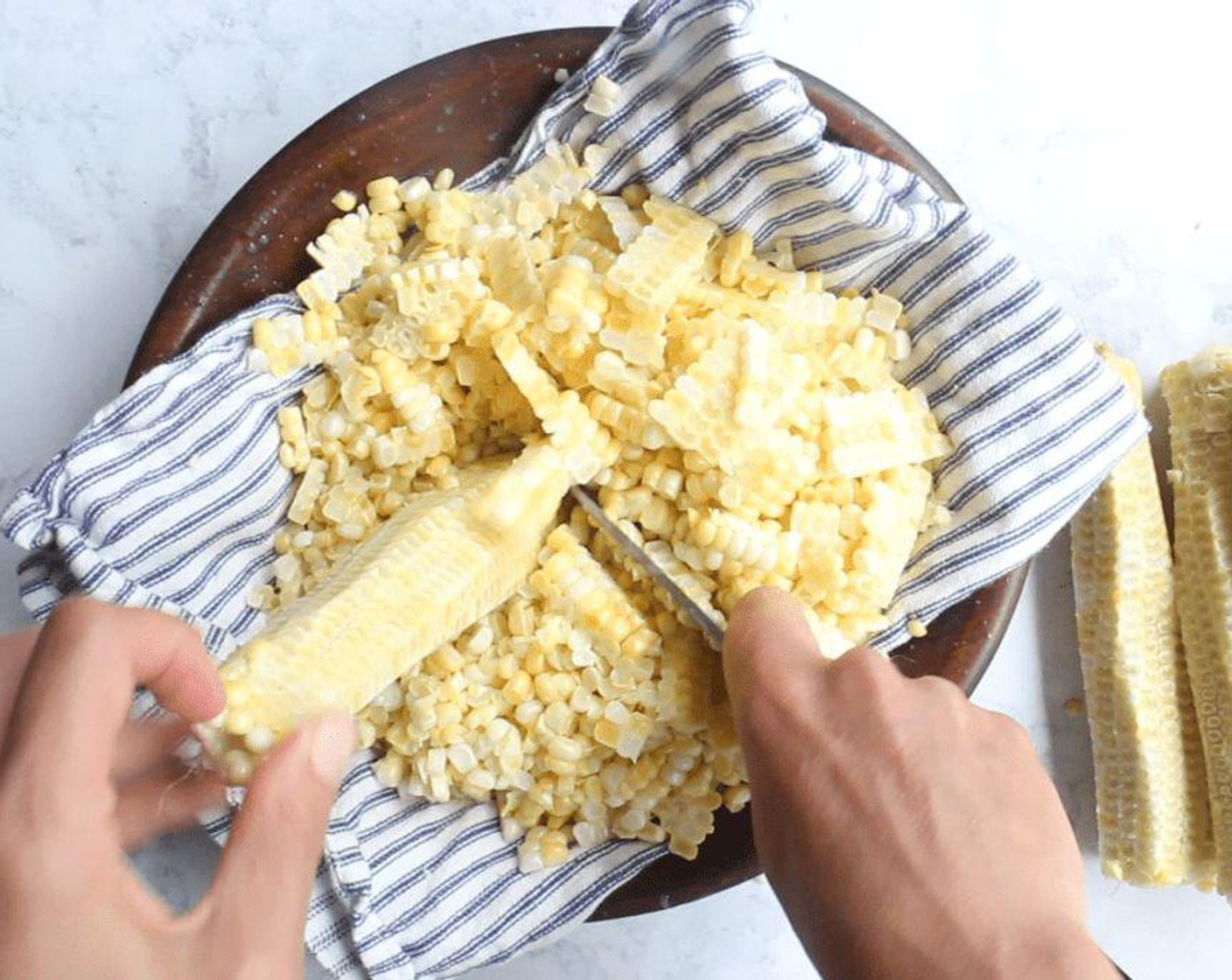 step 1 Fold a kitchen towel into quarters and set it inside a large, wide bowl. Use one hand to hold each of the Corn Cobs (8) in place upright atop the kitchen towel; it helps to pinch the ear at the top. With your other hand, use a chef's knife to cut off two to three rows of kernels at a time by sliding the knife down the cob. Get as close to the cob as you can. Save the cobs.