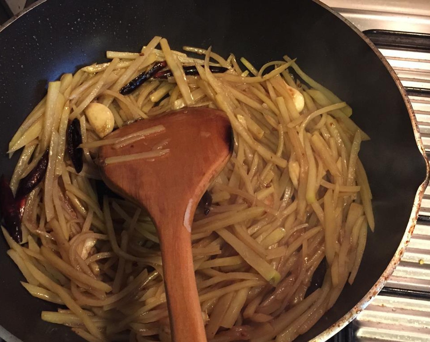 step 6 Add the peeled garlic and halved chili peppers. After a few seconds, add in the drained potatoes. Stir fry until the potatoes are almost translucent but not completely soft.