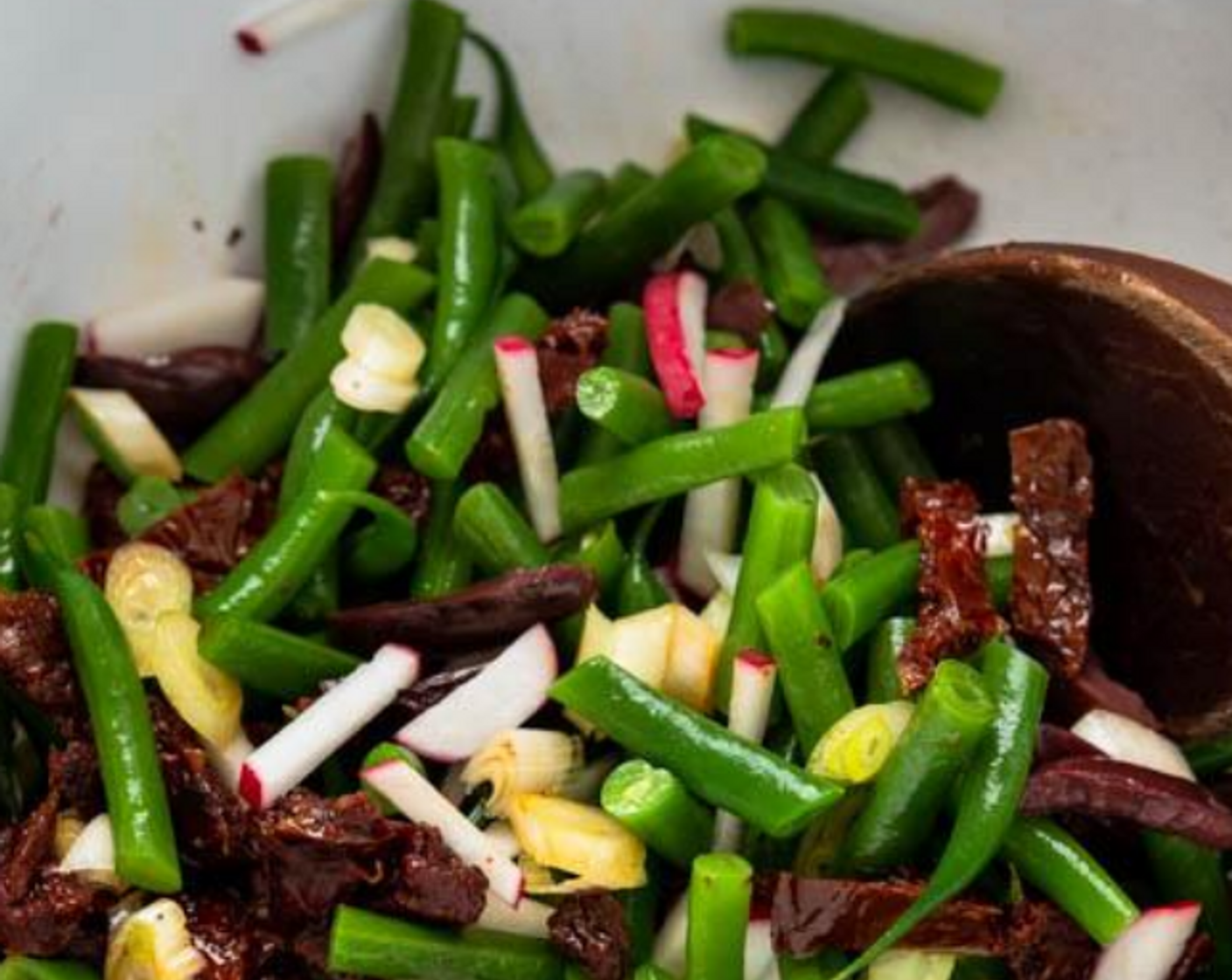 step 9 In a large bowl, combine the green beans, Scallion (1 bunch), Radish (1 bunch), Sun-Dried Tomatoes in Olive Oil (1/2 cup), Kalamata Olives (1/3 cup), and Fresh Mozzarella Cheese Ball (1 cup). Toss to combine.