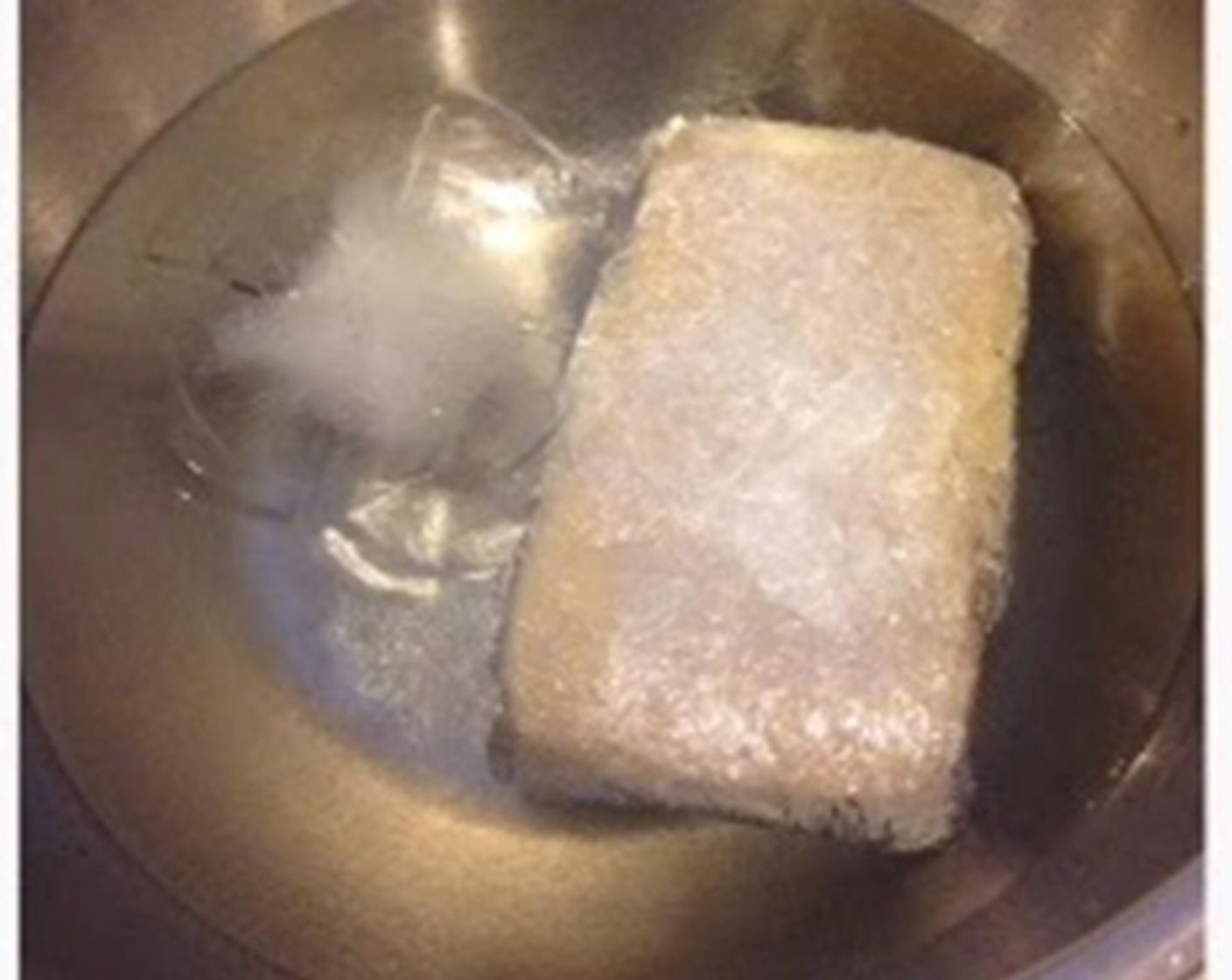 step 2 Prepare ice water in a bowl. Put the pot on the stove and heat to medium heat. Keep stirring until it becomes sticky and glutinous and has a shiny, glossy look. Transfer to cling wrap and wrap it around. Shape it into a rectangle.