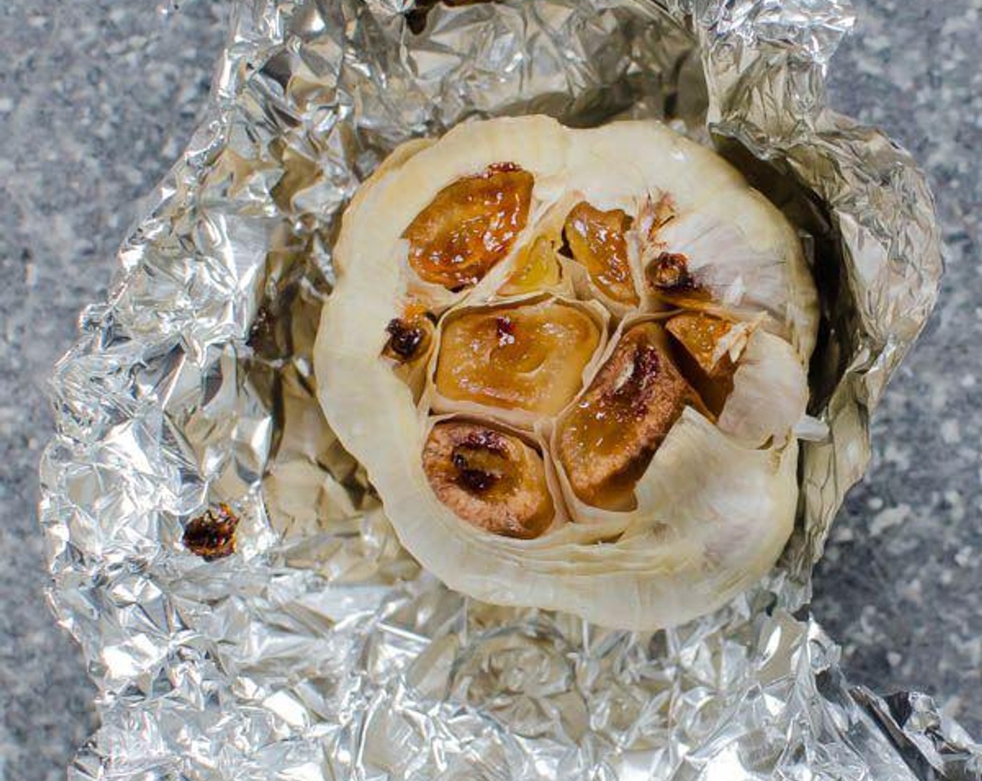 step 2 Slice about 1/4" from the Garlic (1 bulb) and drizzle Olive Oil (1 tsp) over the exposed cloves.  Wrap garlic in aluminum foil and roast for 40-50 minutes, until soft. Remove from oven and cool until you can handle it.
