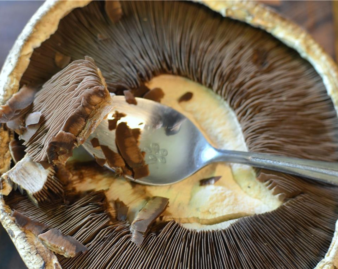 step 2 Then, scrape out the gills with a spoon. Then, wash the mushrooms clean and pat them dry with some paper towels.