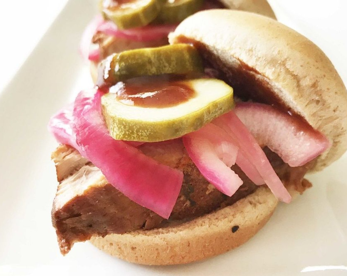 step 8 Place one slice of pork onto a Whole Wheat Slider Buns (10) and top with a few pickled onions, 2 Dill Pickles (20 slices), and a drizzle more of BBQ sauce if desired. Serve and enjoy!