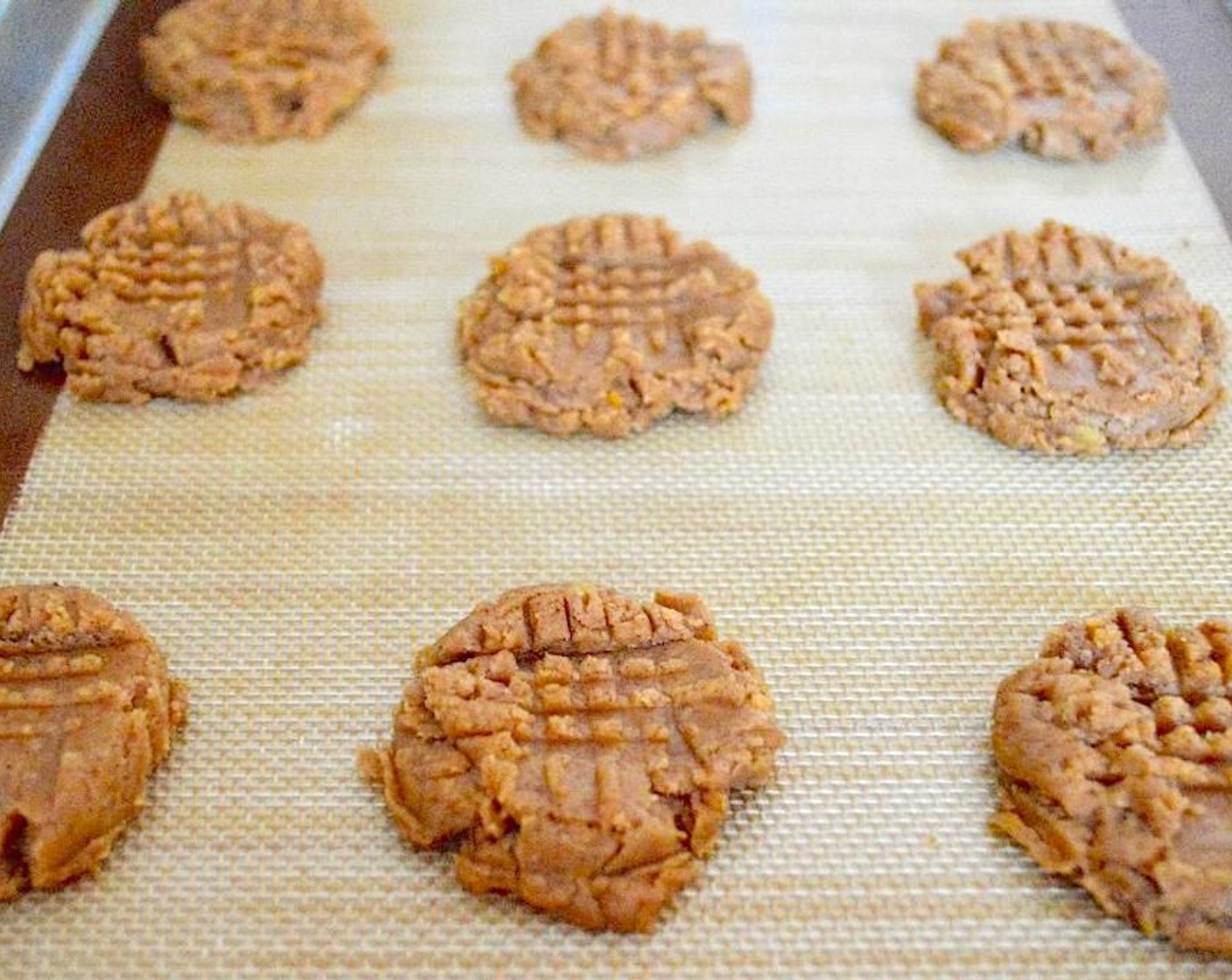 step 4 Use a 1.5-inch cookie scoop to scoop perfect little mounds of the dough onto the lined sheets, with 12 on each sheet. Press each one down with a fork both vertically and horizontally to flatten them out and make those classic cross marks.