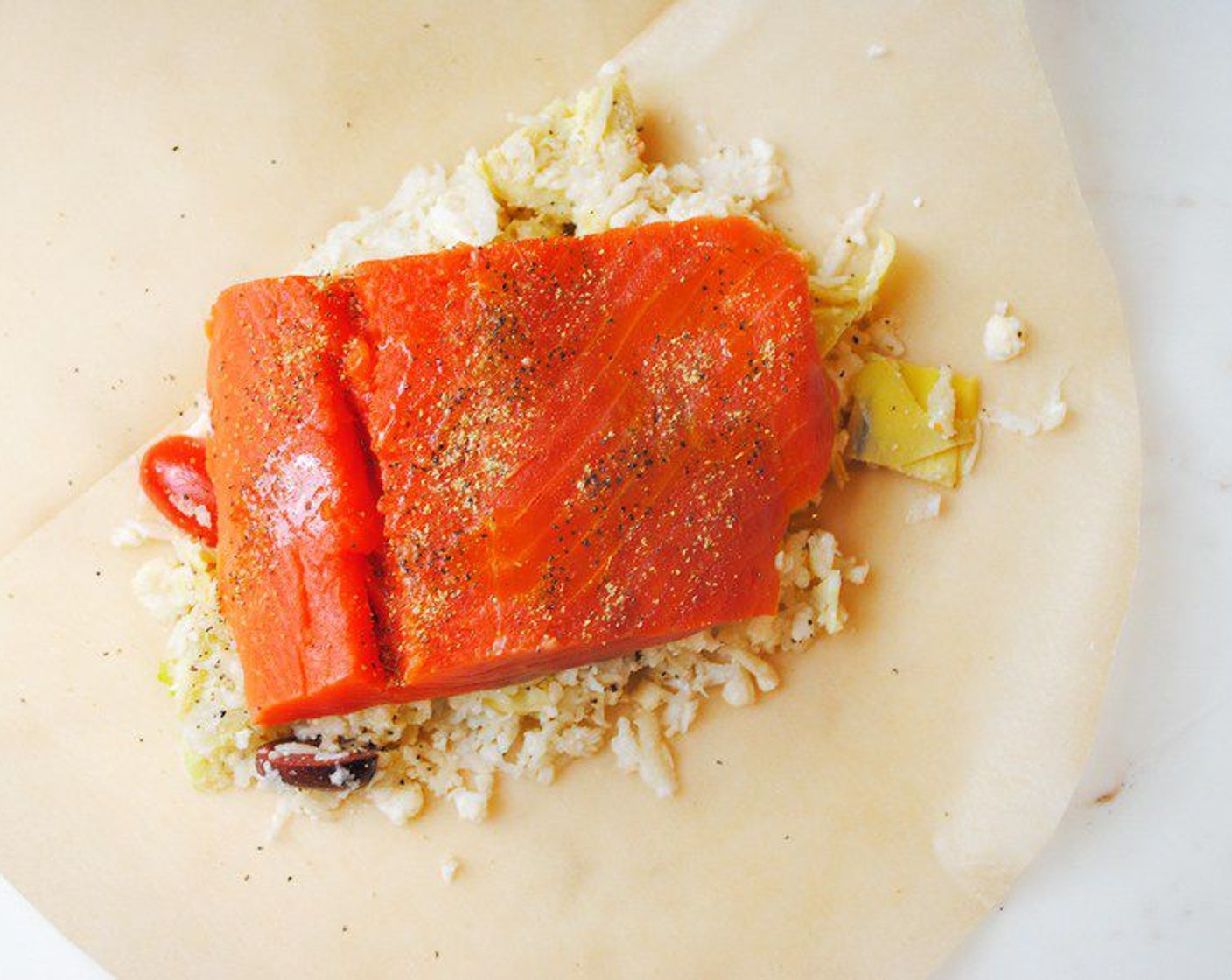 step 4 Put 1 cup of the cauliflower rice mixture into the center of one side of the heart. Place one of the salmon fillets on top and drizzle the Skinless Salmon Fillets (4) with a little Olive Oil (to taste). I like to sprinkle additional Greek Seasoning on top.