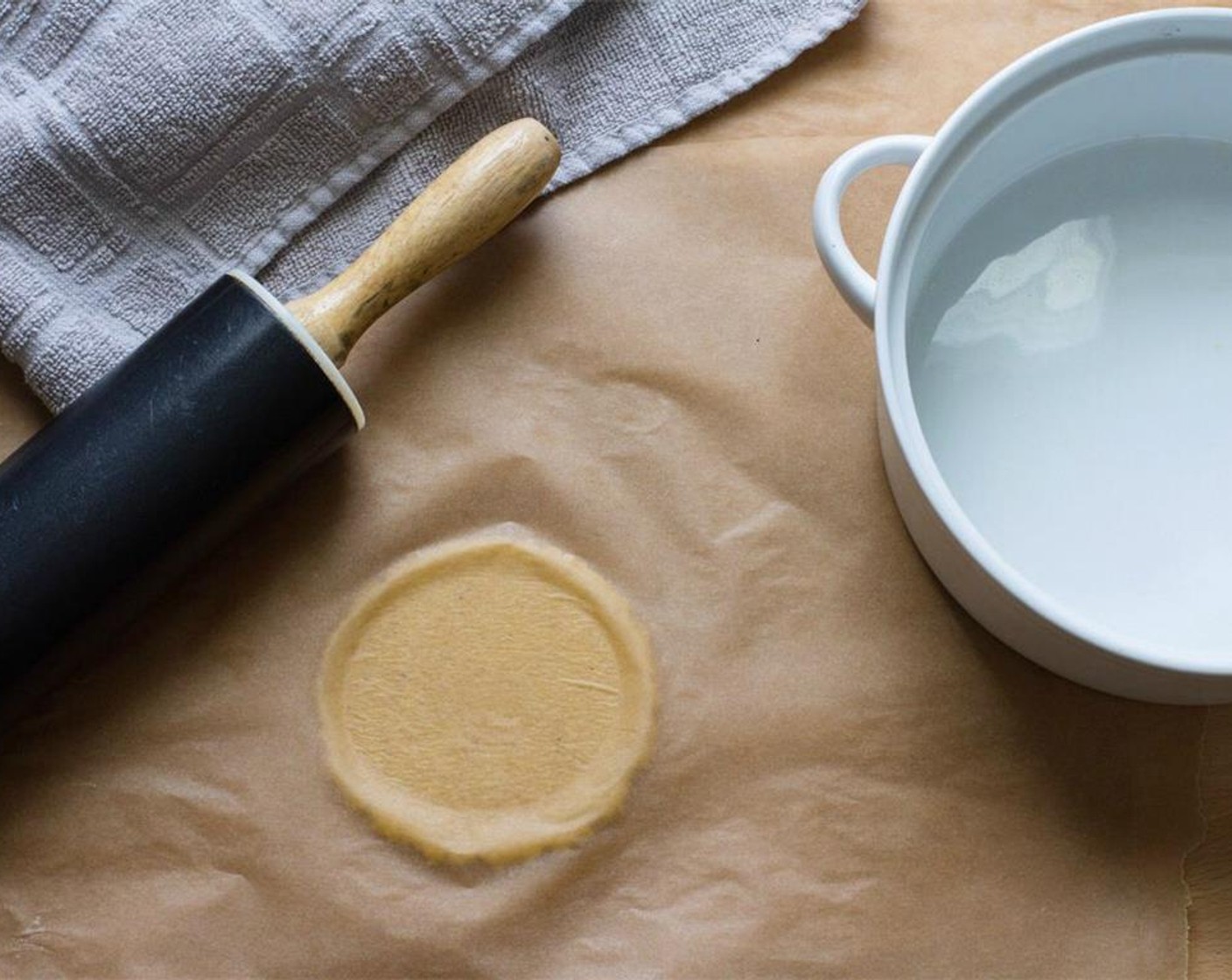 step 8 Place one ball between 2 larger sheets of parchment paper and, holding the plate, use your body weight to flatten the dough.