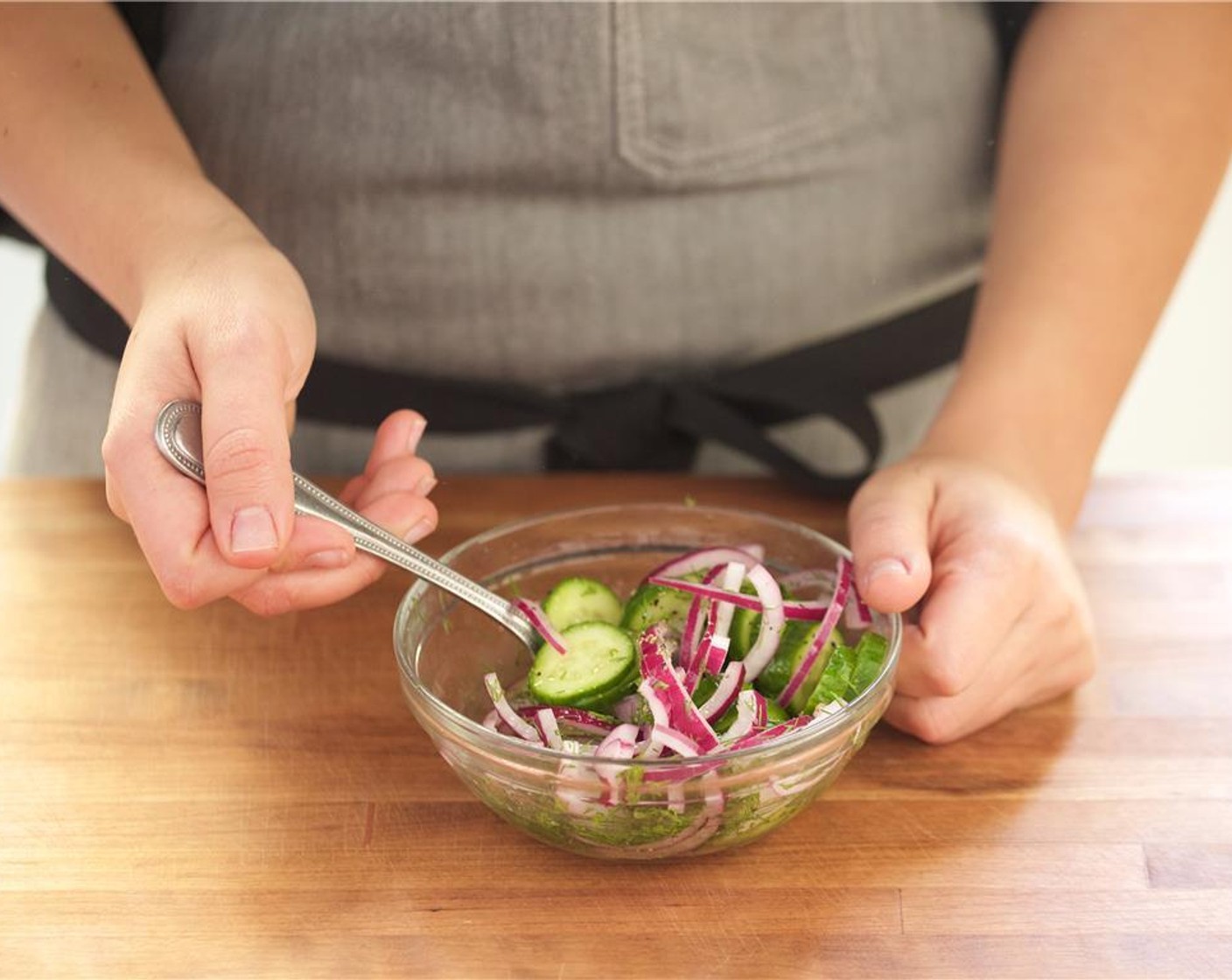 step 3 Cut the remaining Red Onion (1/2)  in half then into quarter inch thin slices and add to the bowl. Cut Persian Cucumber (1) into half inch sliced rounds, and place in the medium bowl.