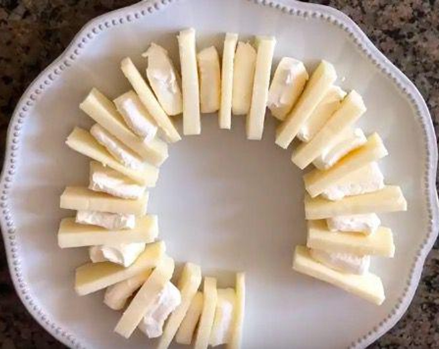 step 4 On a platter, arrange cheese slices upright in a ring with one slice of mozzarella, one slice of Monterey Jack, and one slice of cream cheese until you form a complete circle.