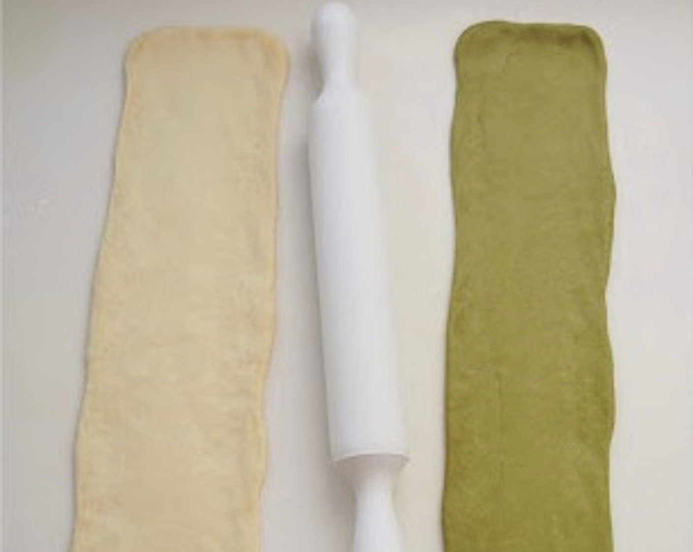 step 7 Punch down each dough to release the air. Transfer the plain dough to a clean floured surface and divide it into 2 equal portions. Shape each plain dough into a long log, about 25 centimeters. Roll out each log with a rolling pin into a long rectangle shape, about 45x10 centimeters. Repeat with the matcha dough.