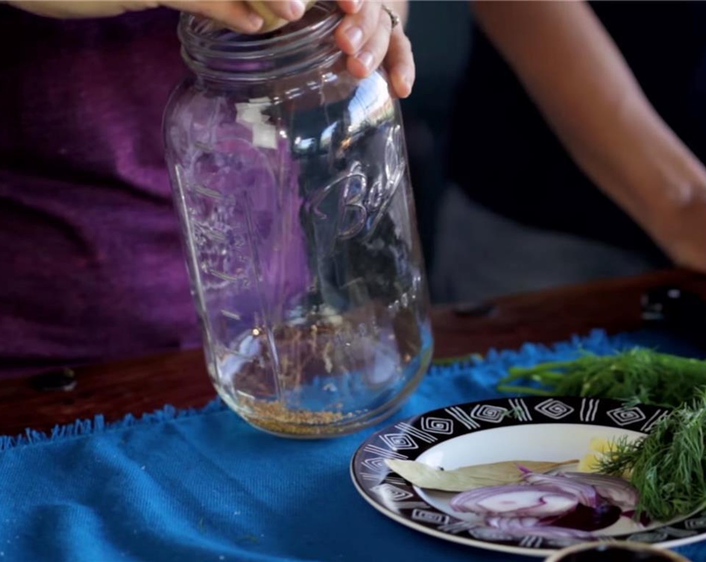 step 3 Combine the Mustard Seeds (1 Tbsp), Fresh Dill (2 sprigs), Bay Leaf (1), thinly slice the Onion (1/4), and peel the Garlic (5 cloves) and place into the bottom of the Mason jar.