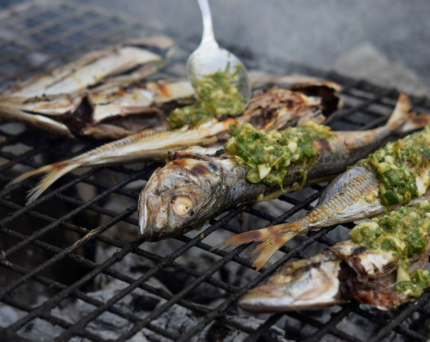 step 5 Once cooked, remove the head and spine of each fish, opening them up like a book. Baste the fishes again with salsa verde.