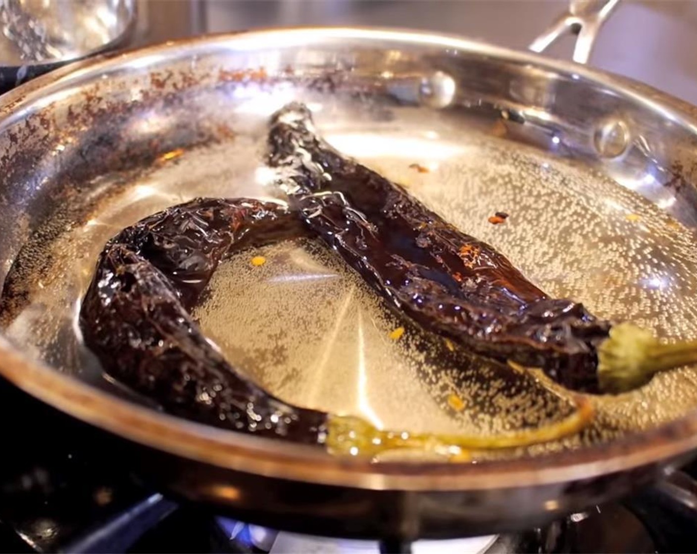 step 2 In a dry pan on medium-high heat, toast the Pasilla Chile Peppers (2), flipping occasionally. Once fragrant, add Water (1 cup) to the pan. Bring water to a low boil. Cook until dried pasilla chilis are soft. Remove, drain, and cut-off tops.