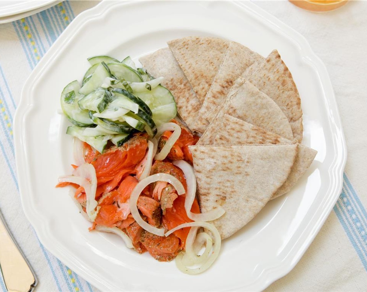 step 10 Place the salmon on one side of the plate, and top with some of the cooked onions. Place a mound of cucumbers next to the salmon. Cut the pita into eight slices and arrange on the plate. Enjoy!