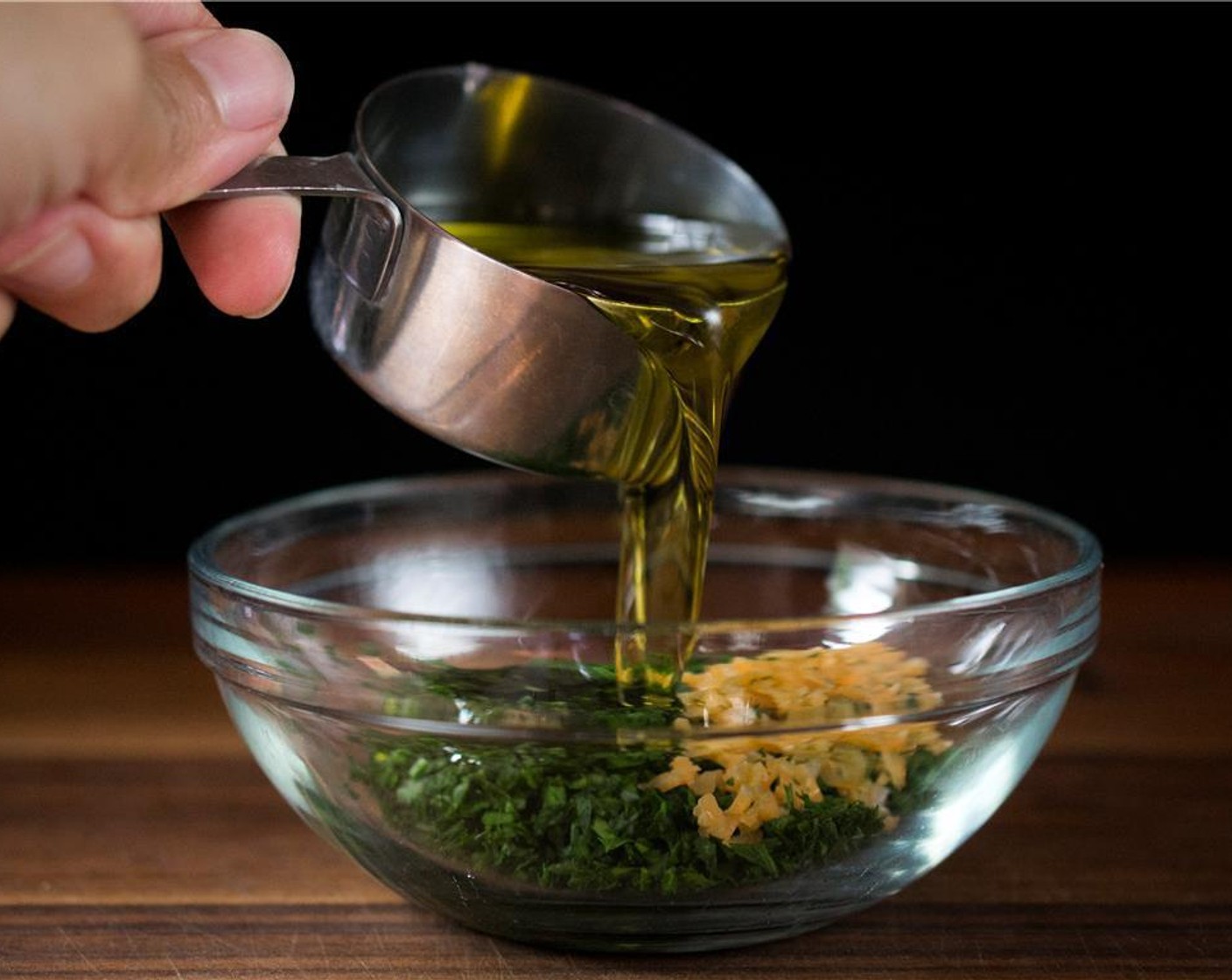 step 4 As the meatballs are baking, prepare the Parsley-Chili Oil simply by mixing Italian Flat-Leaf Parsley (1/4 cup), Habanero Pepper (1), Olive Oil (1/2 cup), and Kosher Salt (1 tsp) in a medium sized bowl. Whisk until well incorporated.