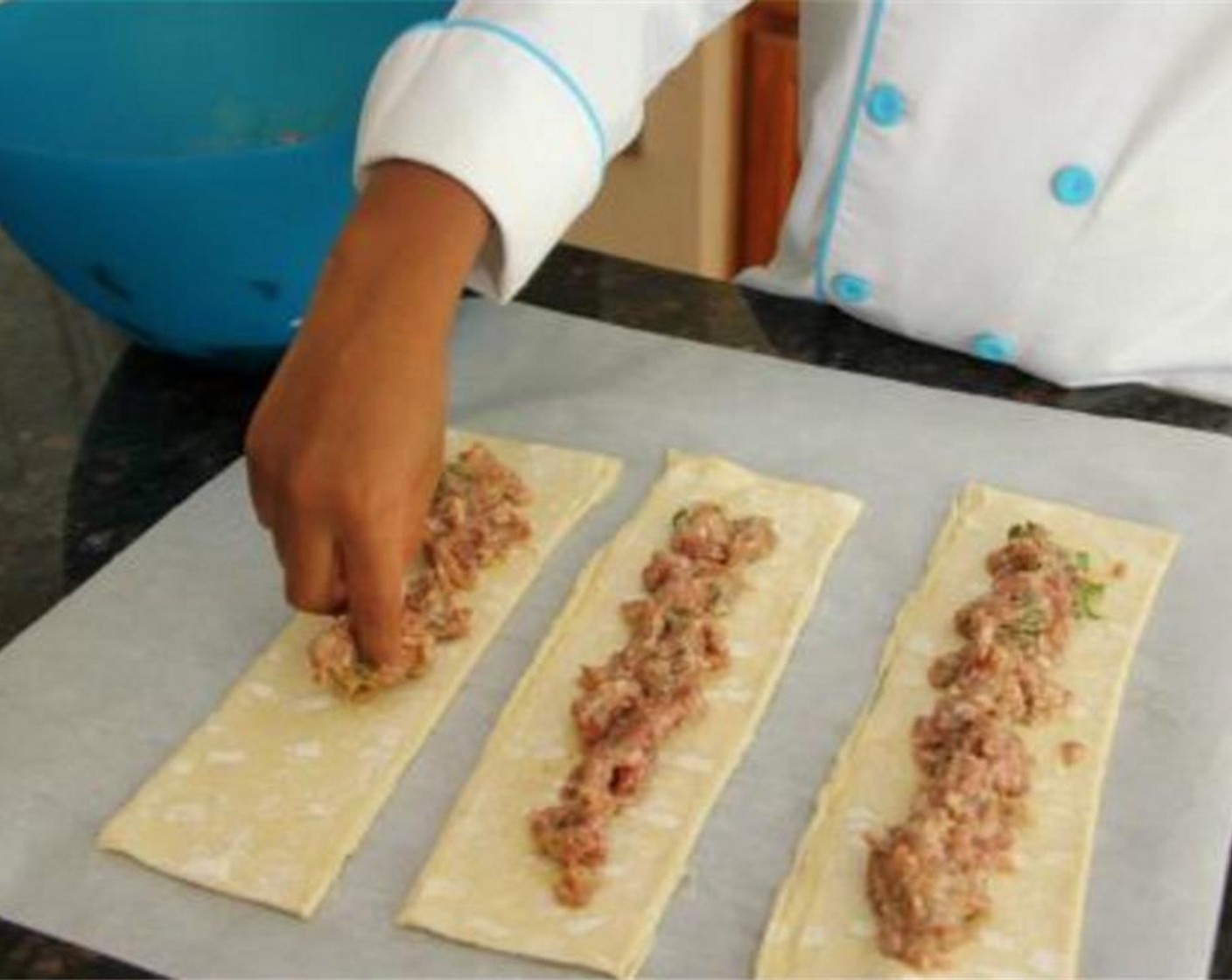 step 4 Take a small amount of the sausage mix and place down the center of puff pastry strips.