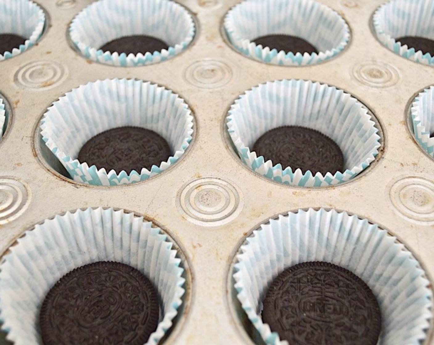 step 2 Get out two muffin tins that can hold 15 cakes total. Line each muffin well with a paper liner and place an Oreo® Chocolate Sandwich Cookies (15) in the bottom of each of the 15 wells.