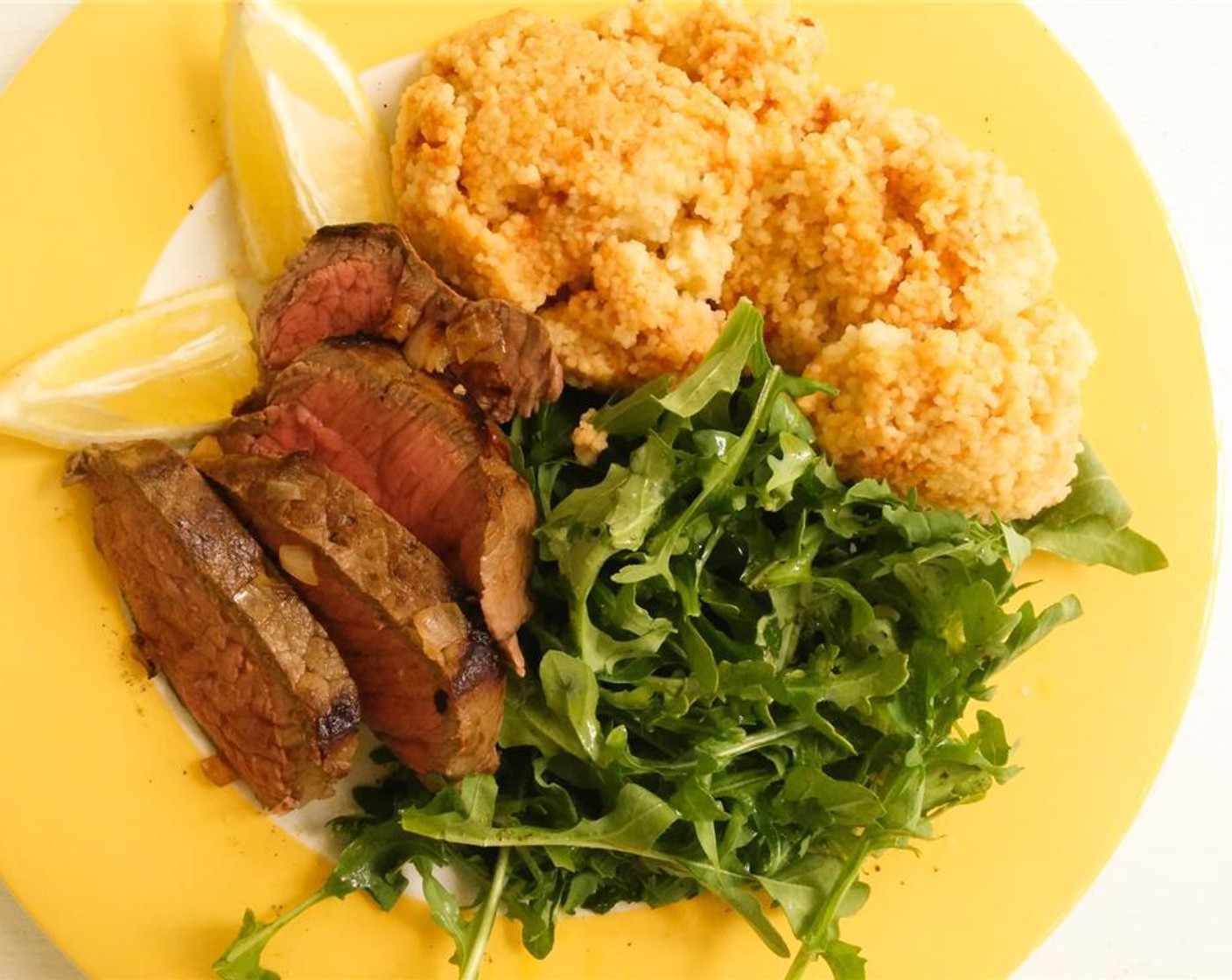 step 6 Take the steaks off the heat and rest for 5 minutes. Slice each steak into 1/2 inch slices against the grain. Arrange the steak on a plate with the arugula and couscous; squeeze over the remaining lemon juice.