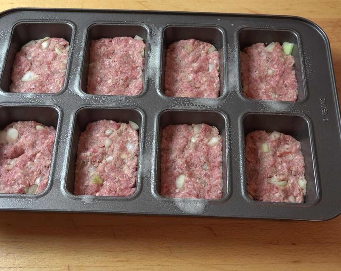 step 4 Press each meatball into its own cup in a greased mini loaf pan. Press them down to fill out the shape, then even out the surface.