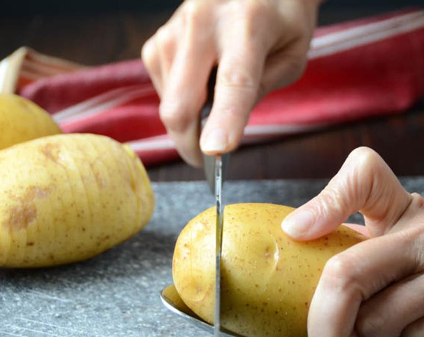 step 11 Place a Yukon Gold Potatoes (4) on a large spoon. Use a sharp knife to cut thin slices, about 1/8-1/4" thick. The edges of the spoon will prevent you from slicing all the way through the potato, creating that accordion effect.