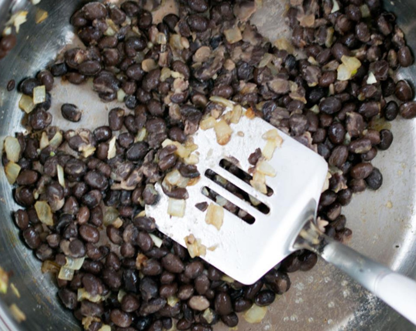 step 1 To make your own refried black beans start by sautéing Yellow Onion (1/2 cup) and Garlic (1 clove) in Extra-Virgin Olive Oil (1 Tbsp) until carmalized, and add in Canned Black Beans (2 1/3 cups) and mash away! I usually use the back of a spatula or a potato masher to get the job done.