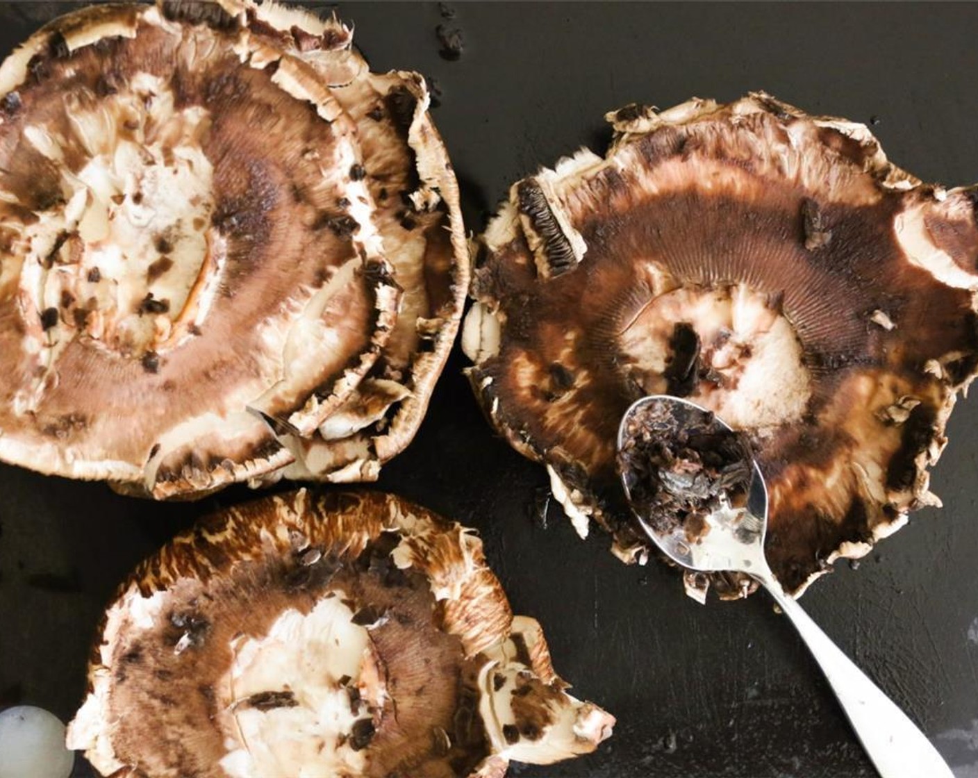 step 5 While the potatoes roast, get going on your Portobello Mushrooms (4). Start by prepping the mushrooms, wash the caps well, pat them dry, and remove the stems. Using a spoon, remove the dark gills from their undersides.