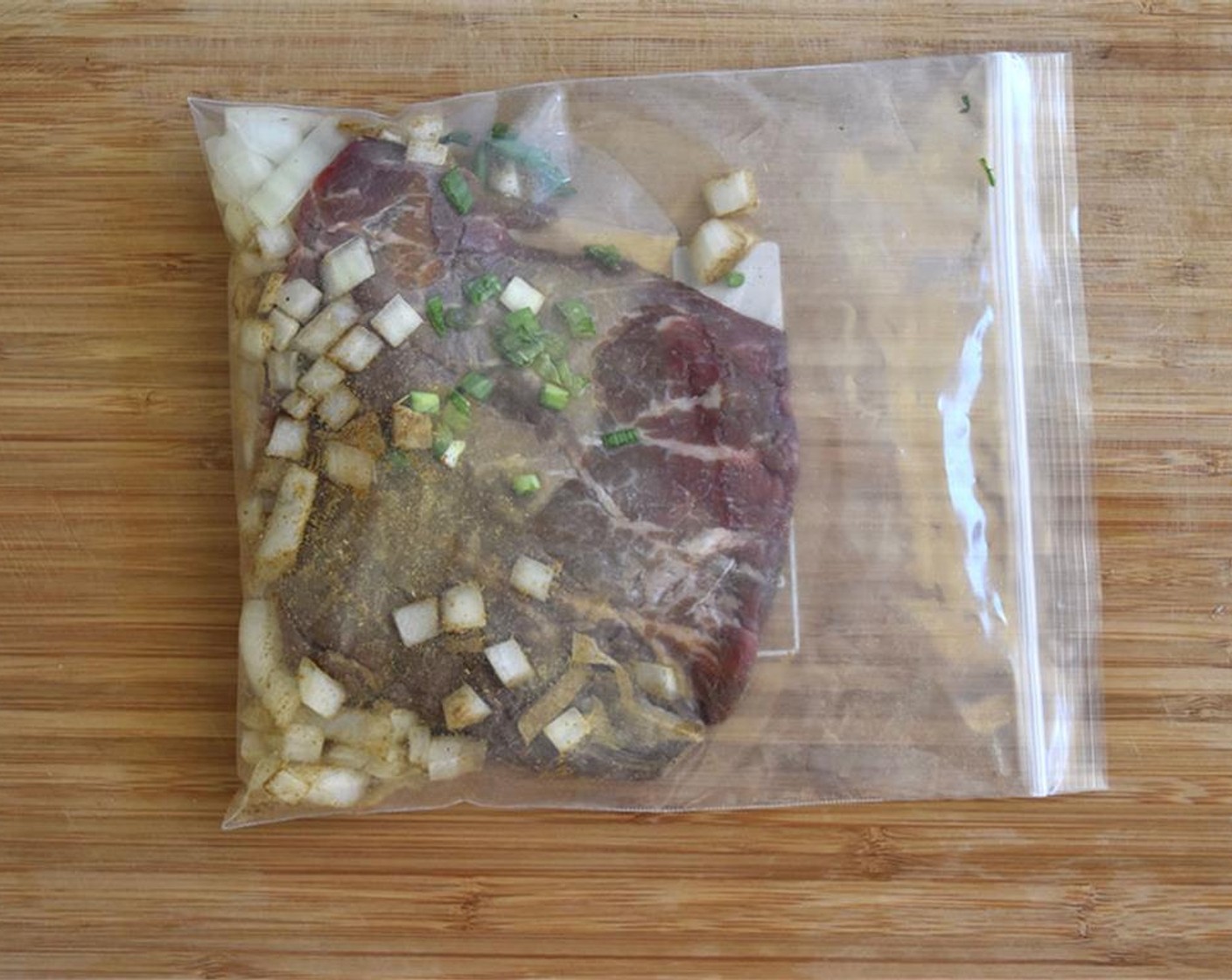 step 5 Place Flank Steak (1 lb) in a plastic bag with Garlic (2 cloves), Scallions (2), Onion (1), Ground Cumin (1/4 tsp), Salt (1 pinch), and Ground Black Pepper (1 pinch) in a bag. Let marinate in fridge for 3 hours.
