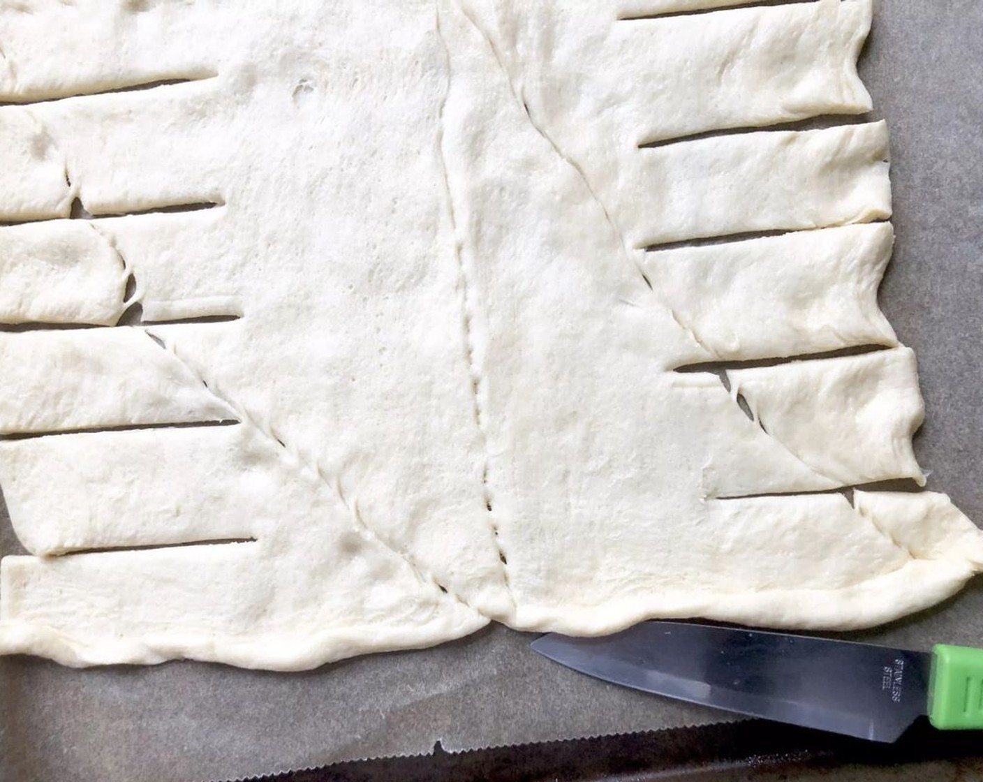 step 5 Unroll the Crescent Dough Sheet (1 pckg) onto the prepared baking sheet. With the short side of the dough closest to you, cut 12 horizontal slits on each of the outer two-thirds of the dough, leaving the center one-third uncut.