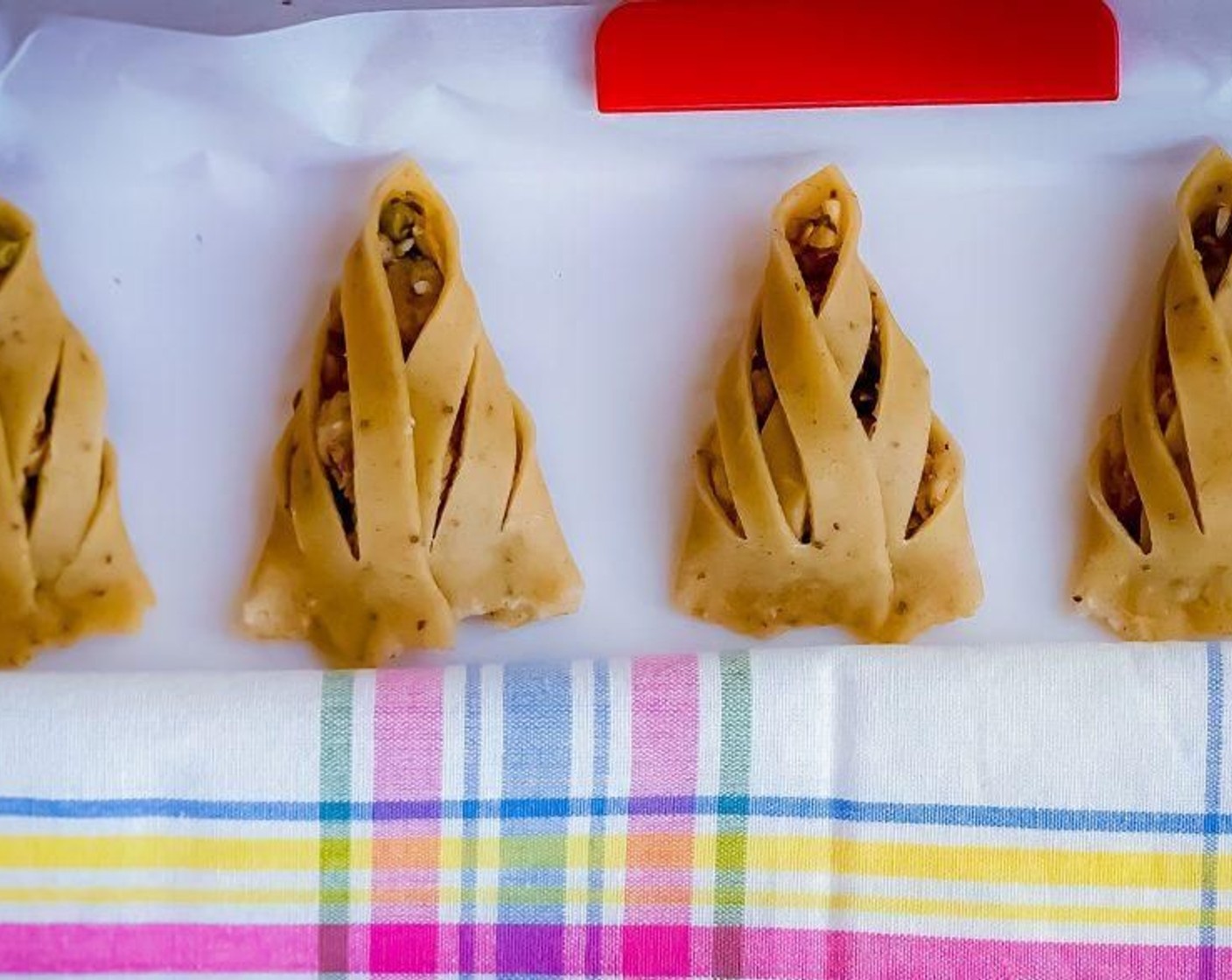 step 19 Place on a baking sheet. Repeat the same process with remaining pieces and rest of the dough. As you go making them remember to keep the filled samosa covered with a kitchen towel so that the crust doesn’t dry out. Leave some gap between them without overcrowding.