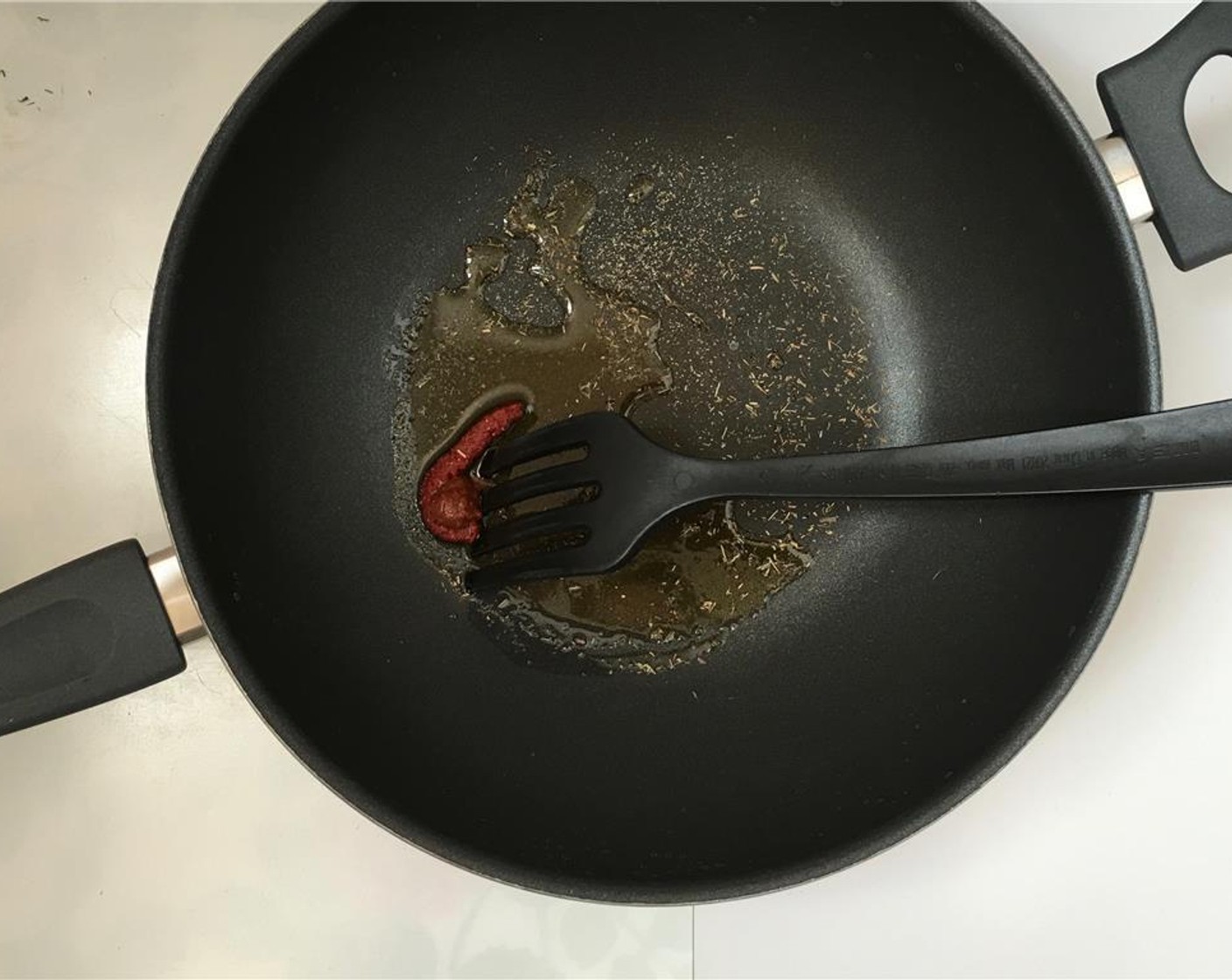 step 6 Add Olive Oil (1 Tbsp) to a large wok together with the Tomato Paste (1/2 Tbsp) and another sprinkle of Ground Black Pepper (to taste), Salt (to taste), and Dried Mixed Herbs (to taste).