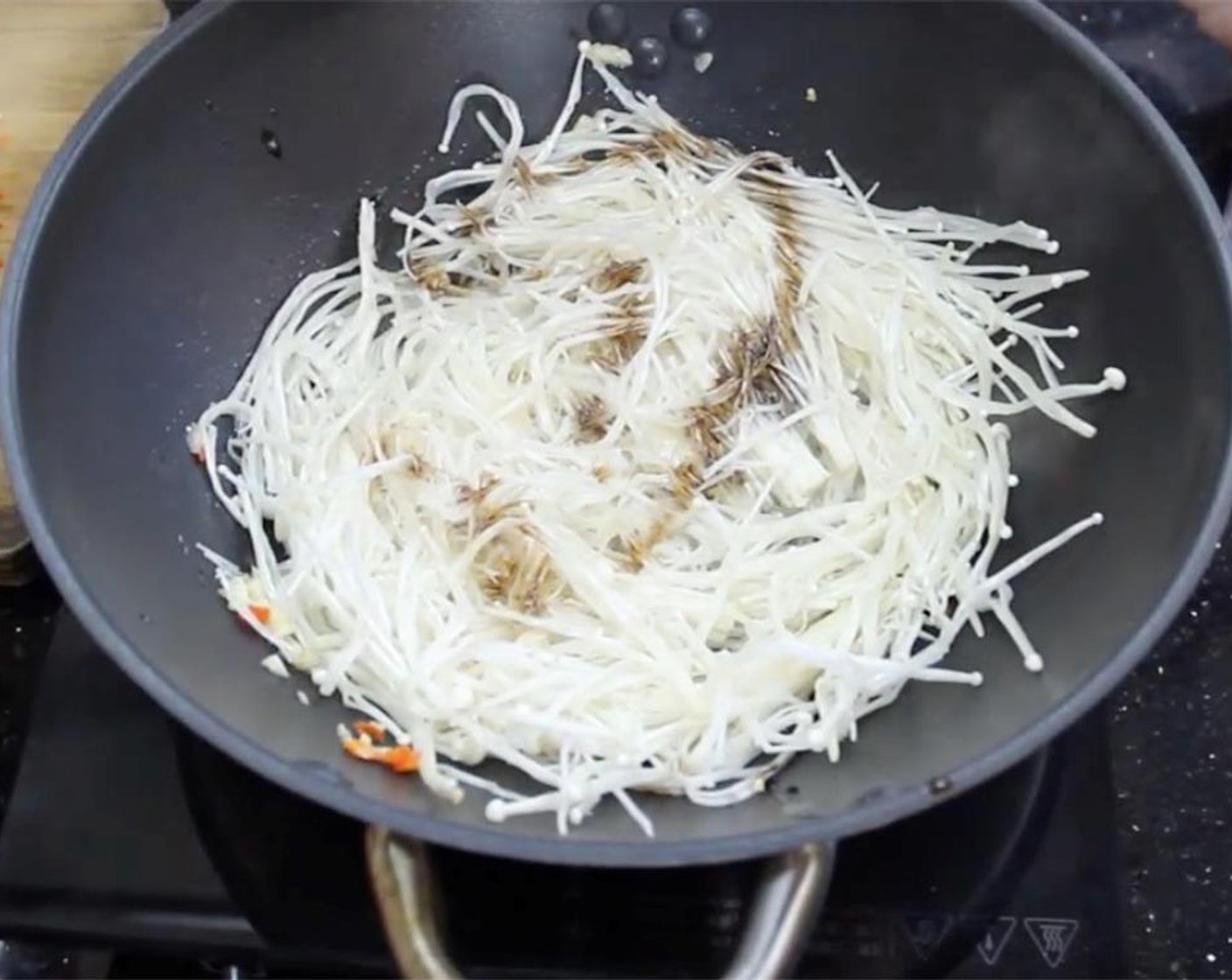 step 5 Add in enoki mushrooms. Drizzle on some Soy Sauce (to taste). Season with Salt (to taste) and Ground Black Pepper (to taste). Saute until water from mushrooms is released.