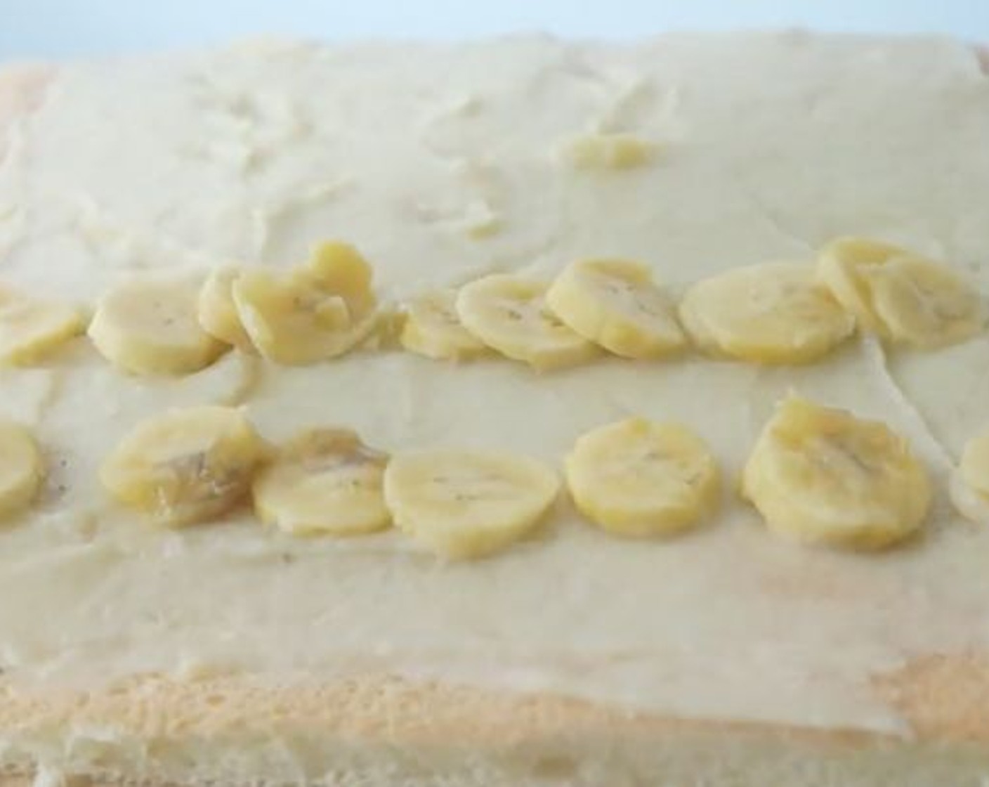 step 19 Spread a layer of banana custard on the sponge cake. Line the cake with sliced bananas.