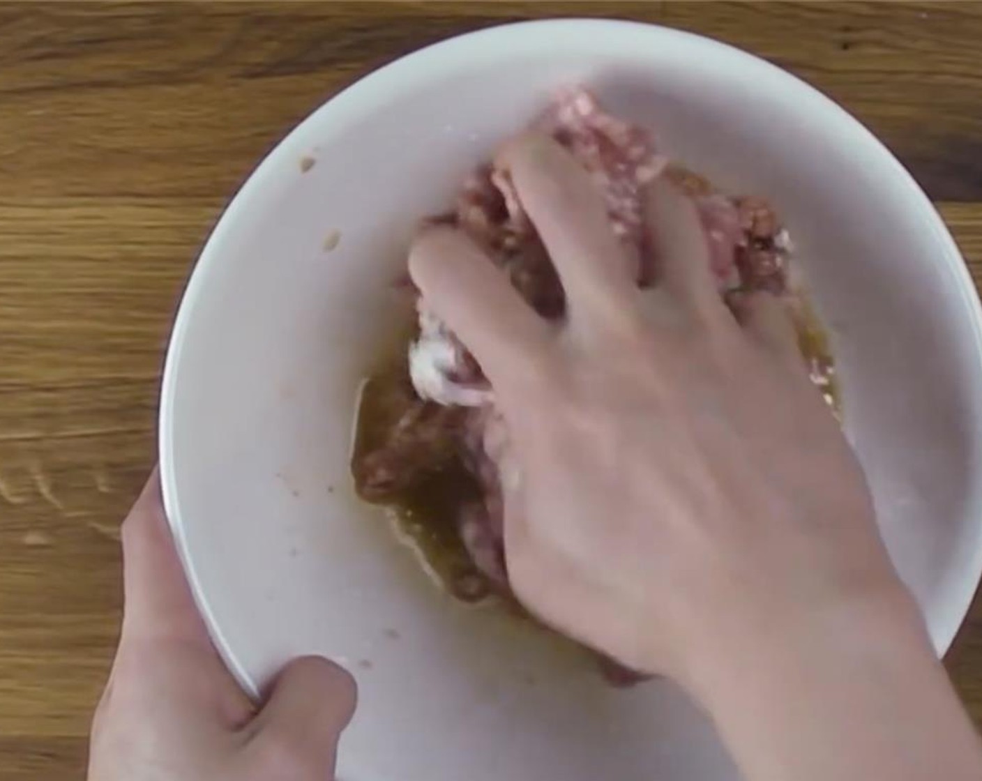 step 4 Squeeze and mix the seasoned ground pork with your hands, then throw it against the mixing bowl until it resembles a paste-like consistency.